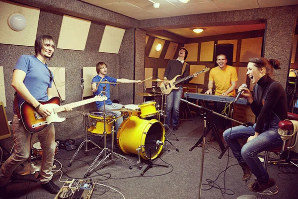 Five-piece band rehearsing together in a music studio