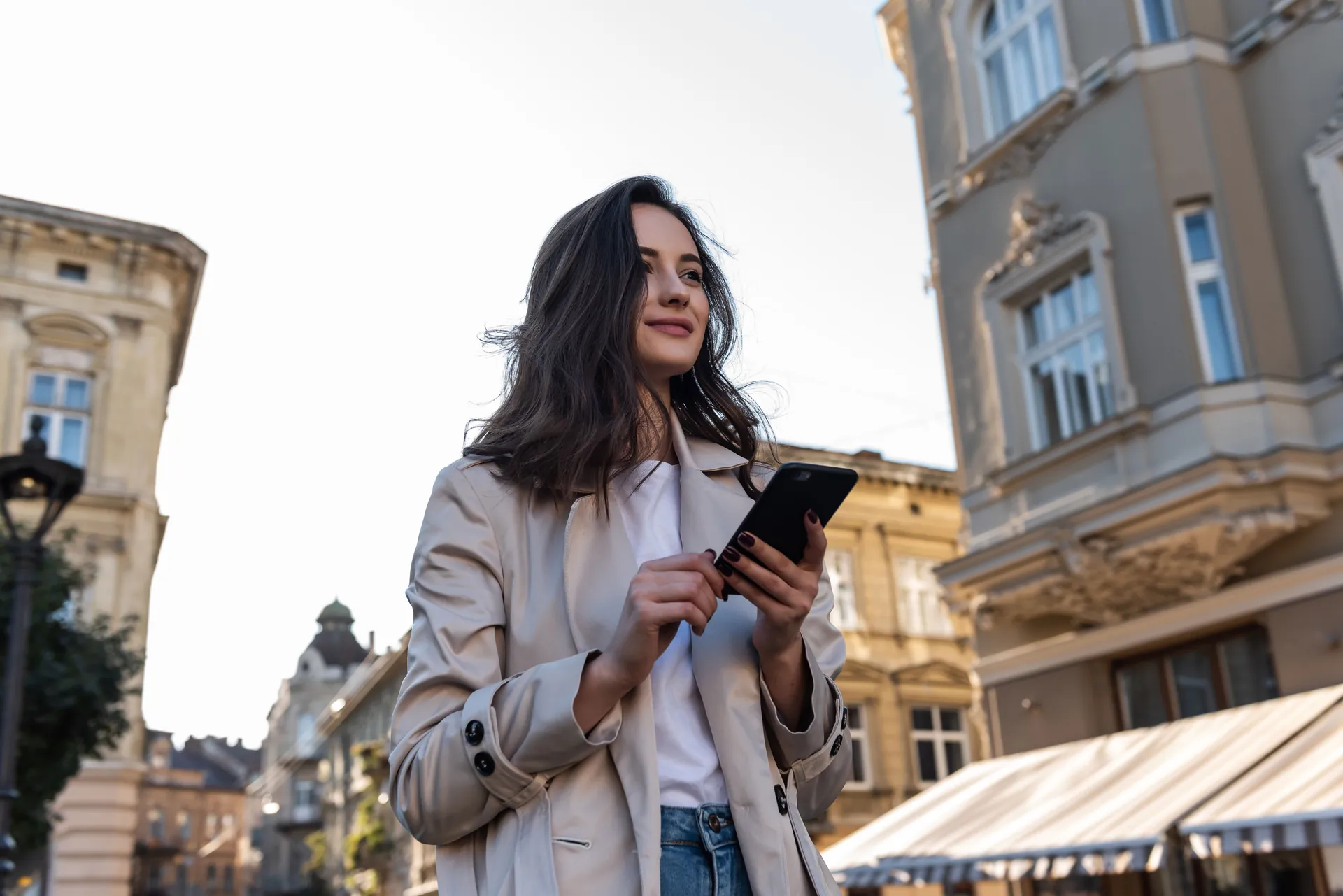 Woman checking her phone on a city street, where most non-broadcast ads reach people