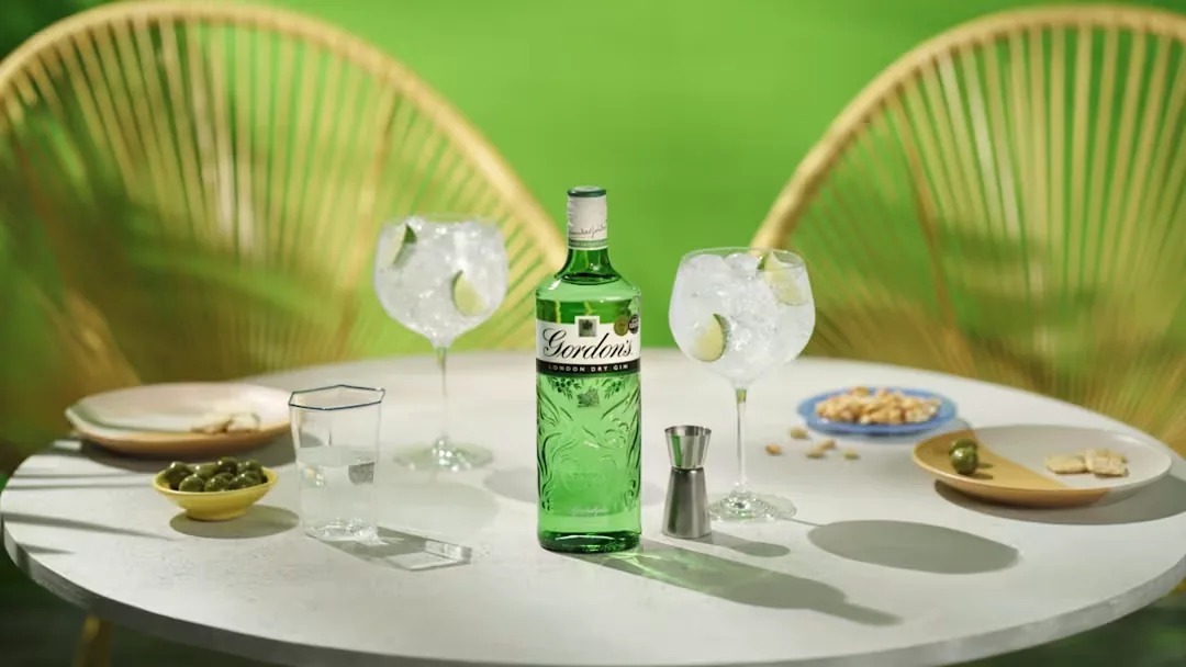 Gordon's London Dry Gin bottle with two gin and tonics on a garden table