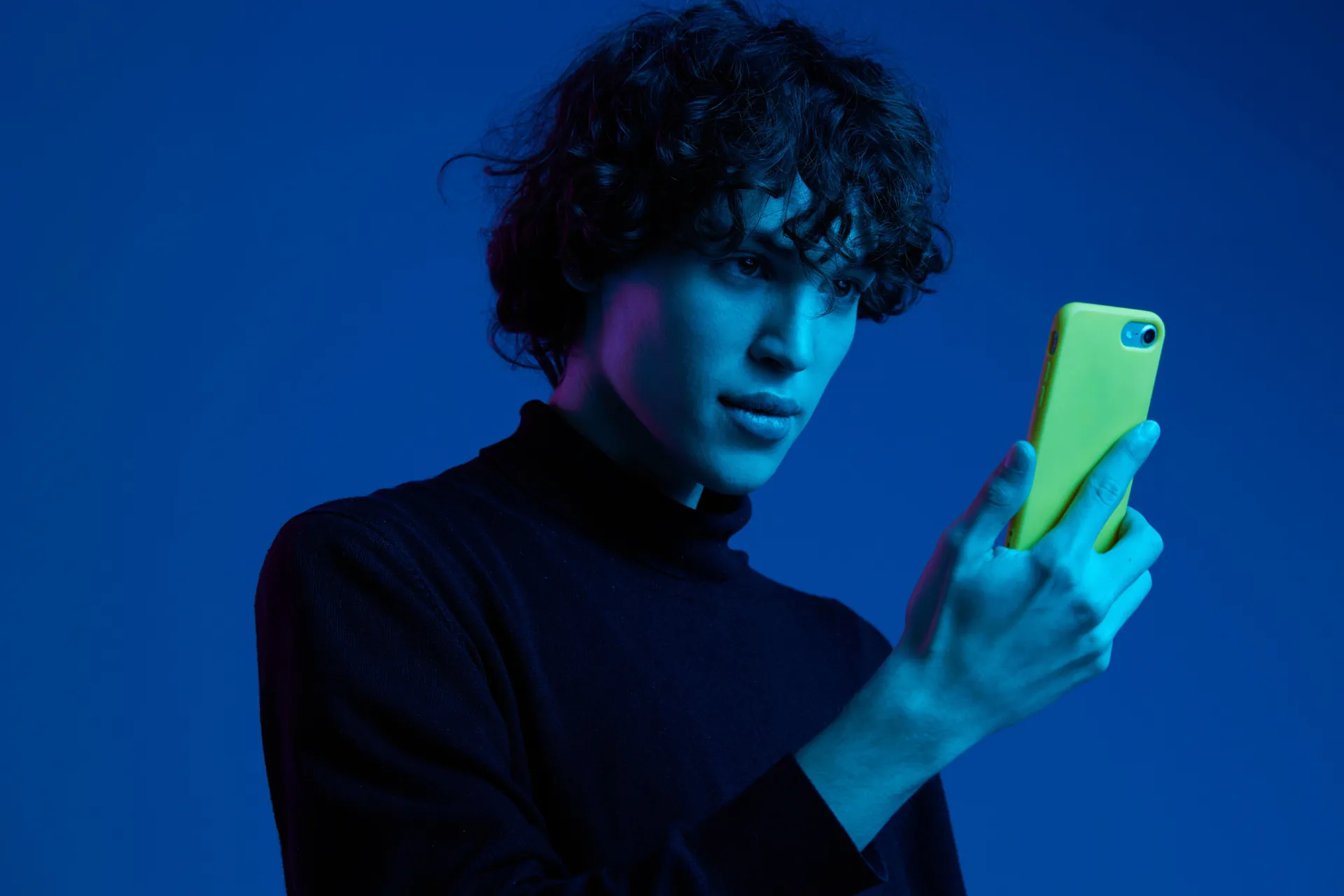 Man scrolling on his phone against a blue background