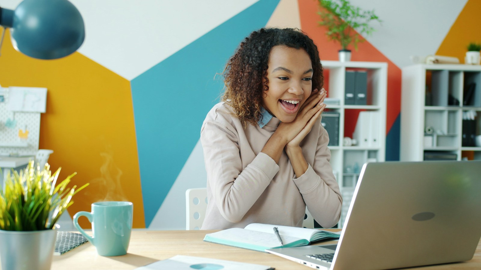 Brand manager smiling at her laptop with a coffee
