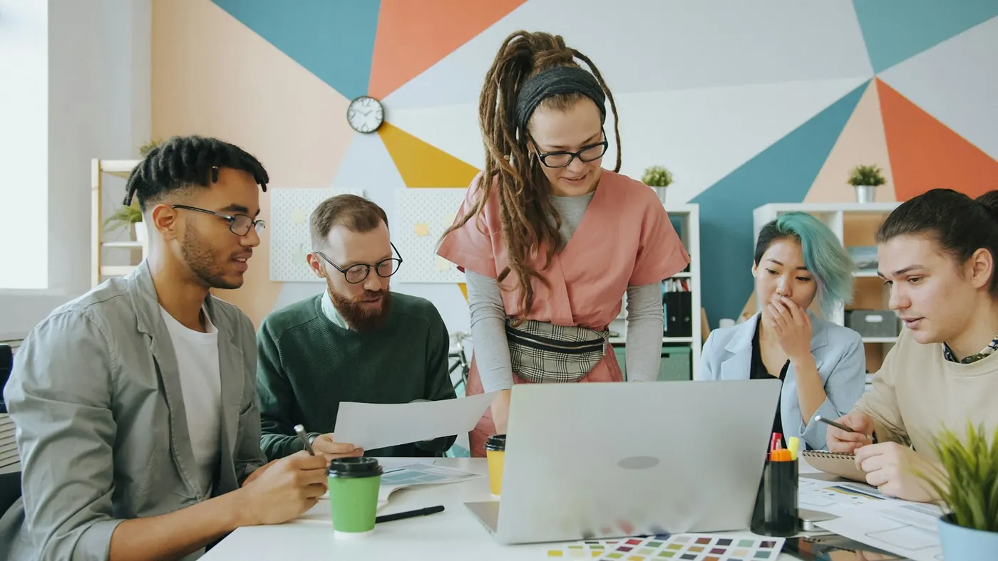 Brand team gathered around a laptop in a colourful office