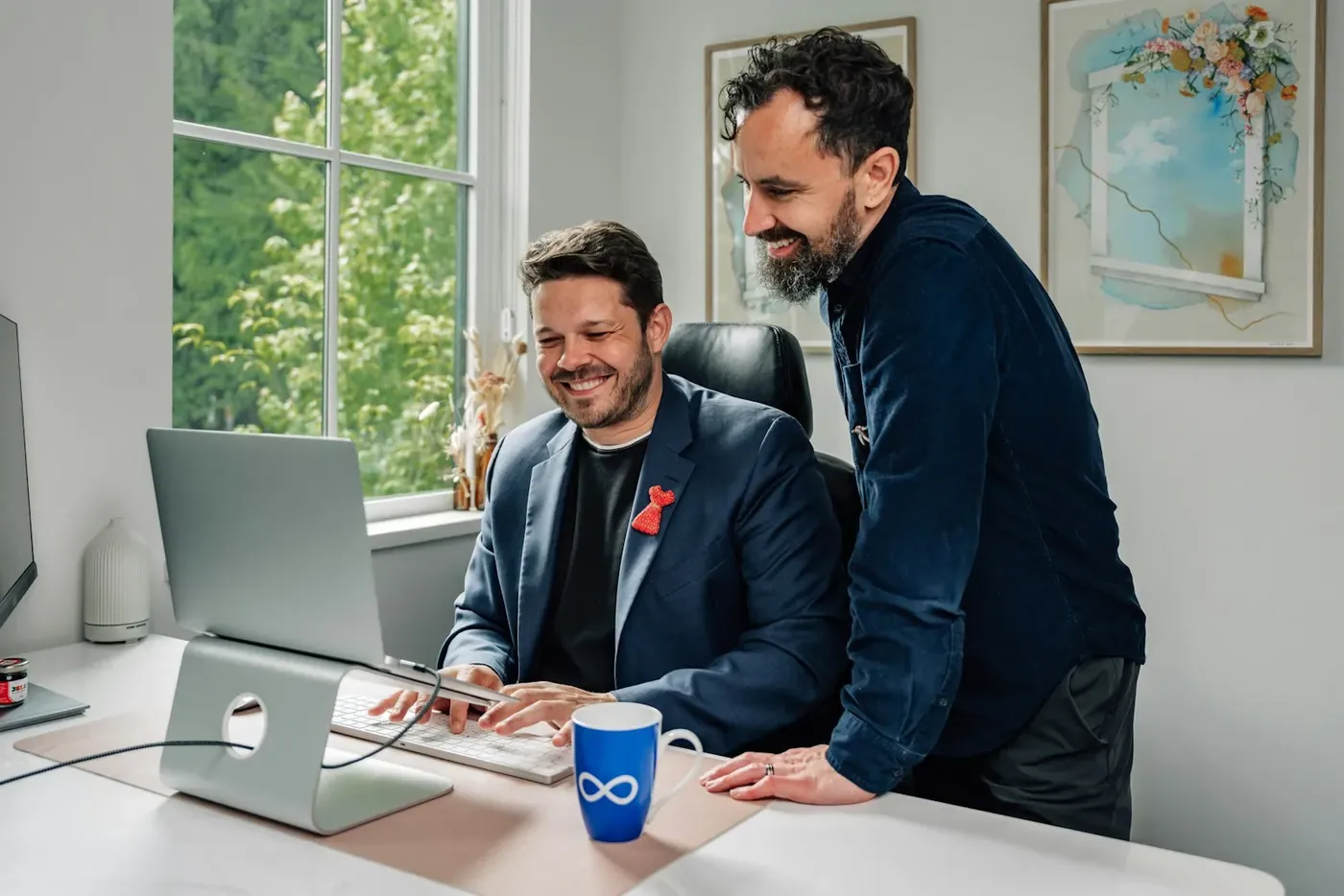 Two colleagues smiling at a laptop after Voxly Vision posted an ad compliance verdict in Slack