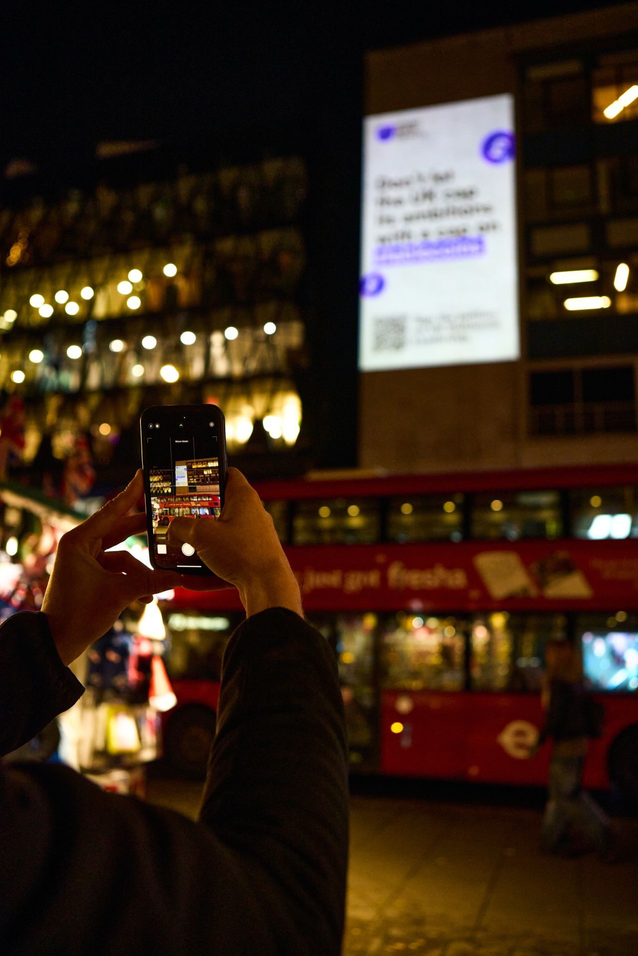 Passer-by photographing a Stand With Crypto projection above a London street at night