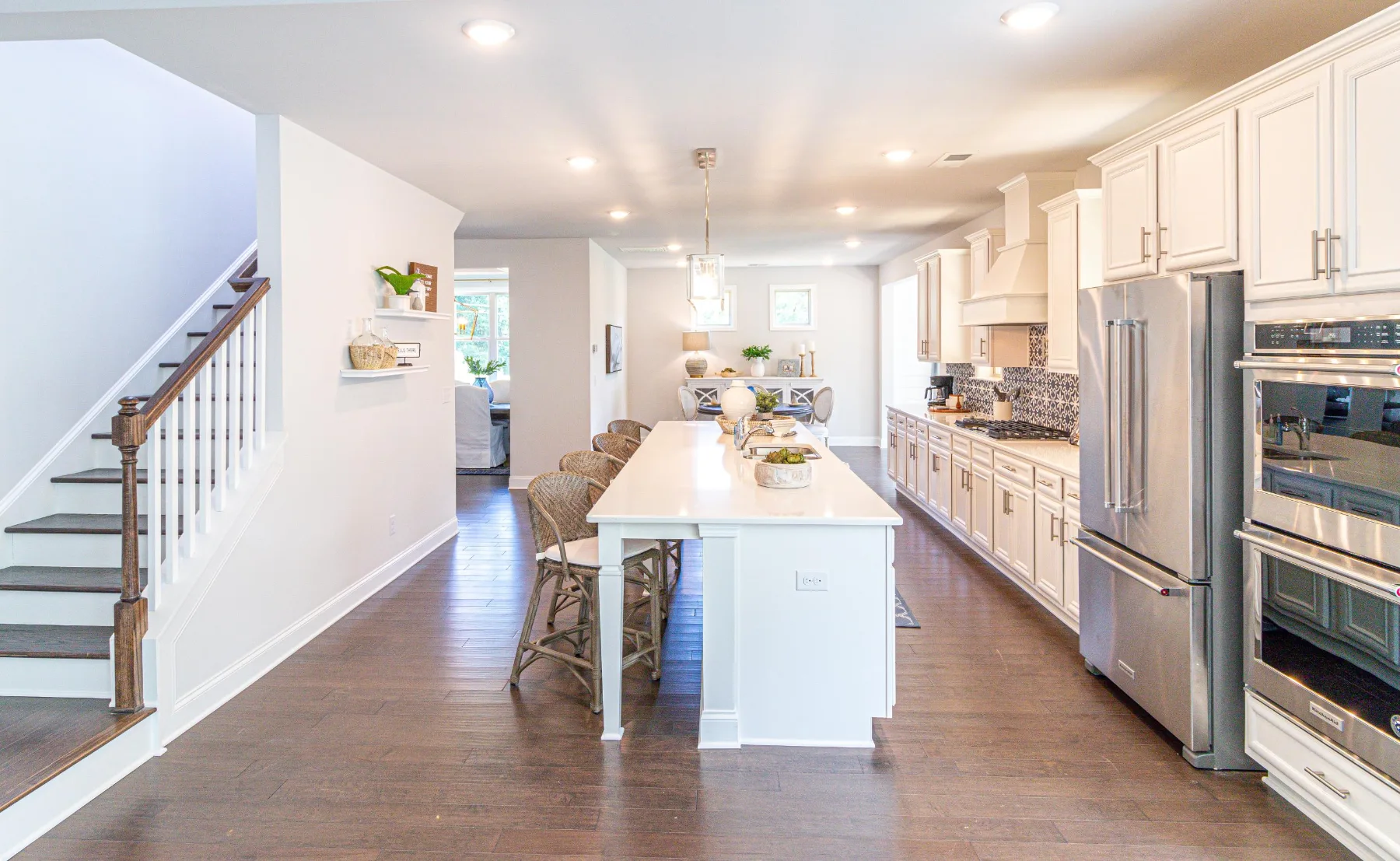 Bright white kitchen with a long center island and stainless appliances