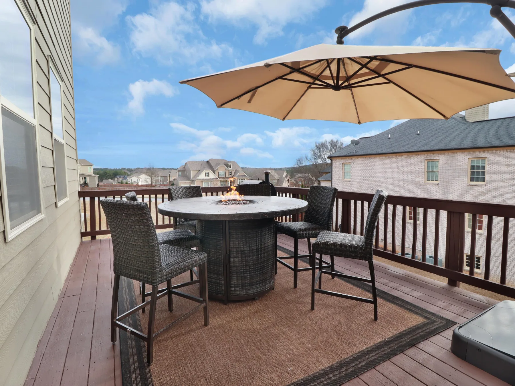 Covered rear deck with outdoor dining overlooking a new-construction neighborhood