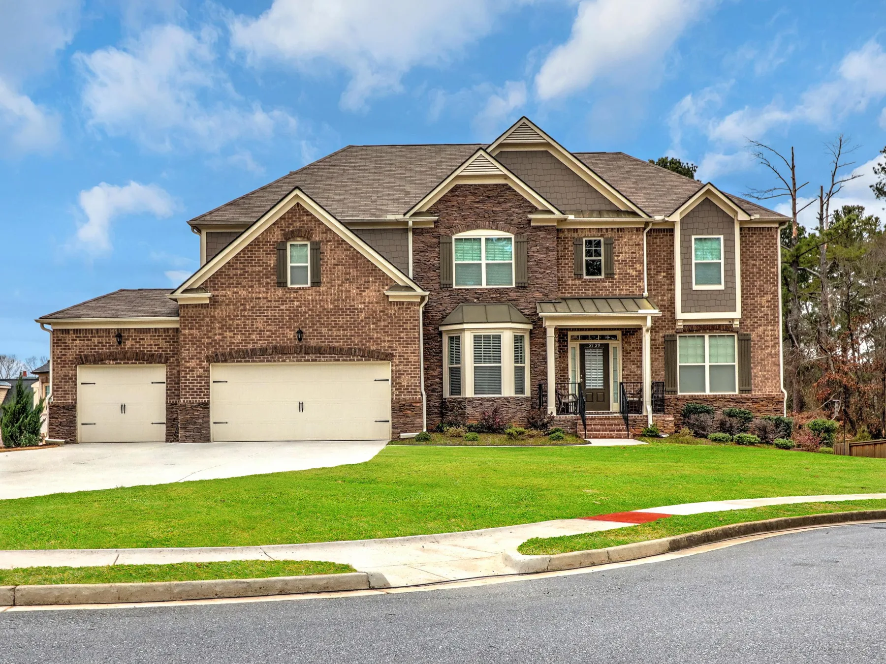 Two-story brick home with a front lawn and landscaped beds