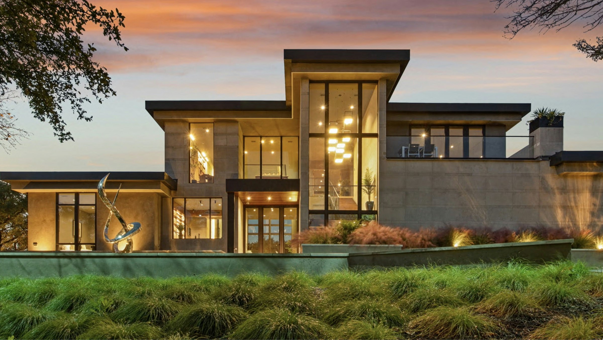 Modern luxury home with large windows glowing at dusk