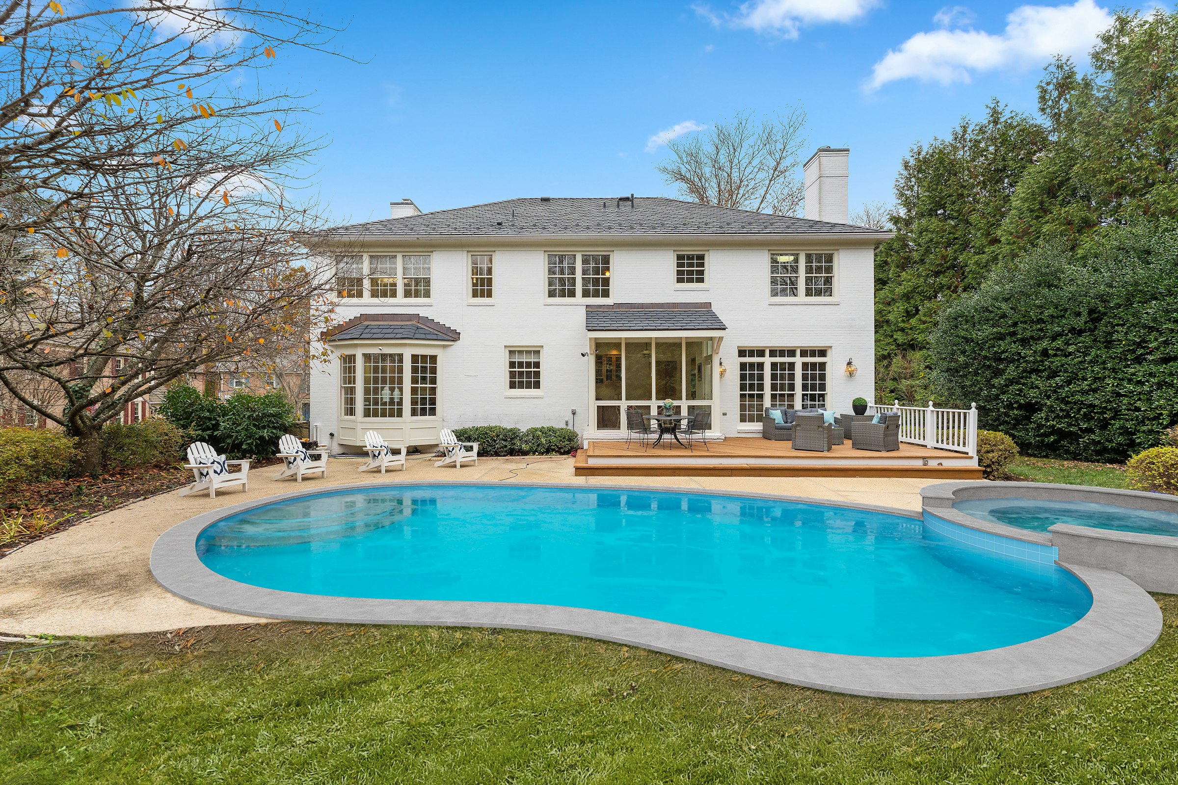 White two-story home with a backyard swimming pool on a sunny day
