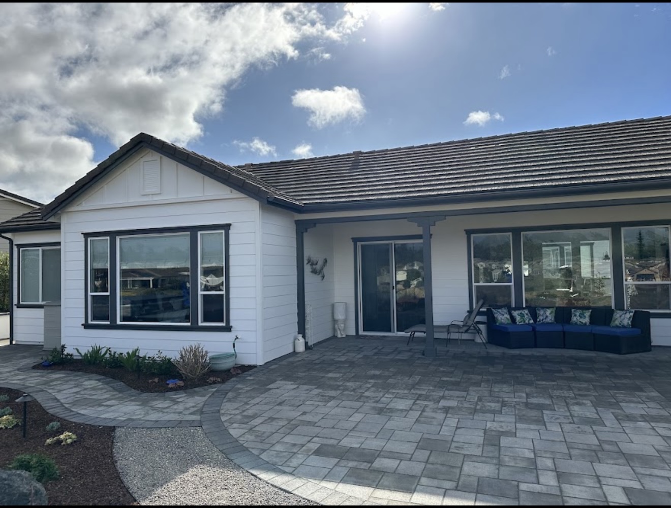 Finished residential exterior painting project with white siding and dark trim by Coastline Painting