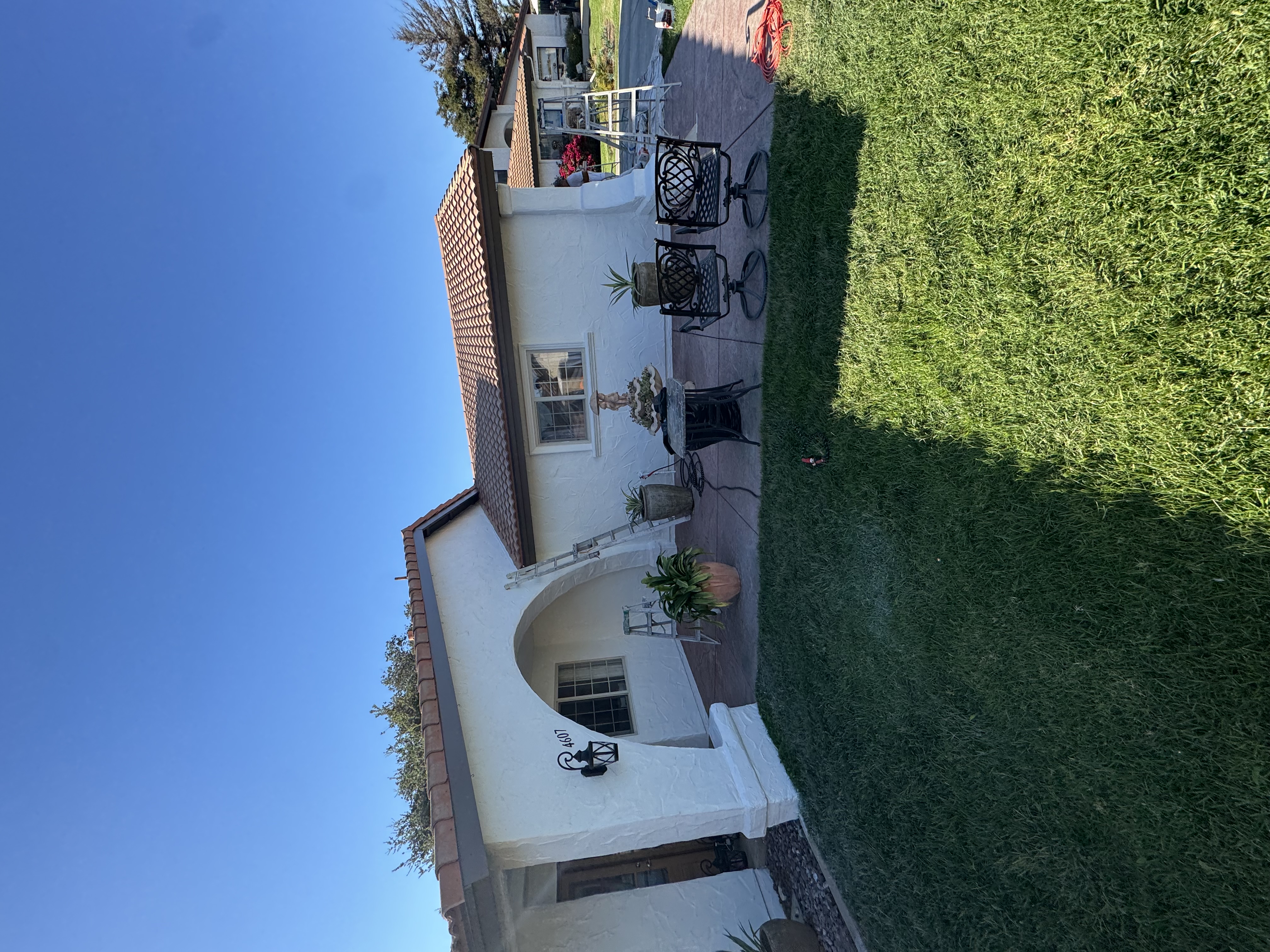 Exterior painting project showing a light stucco house and landscaped backyard
