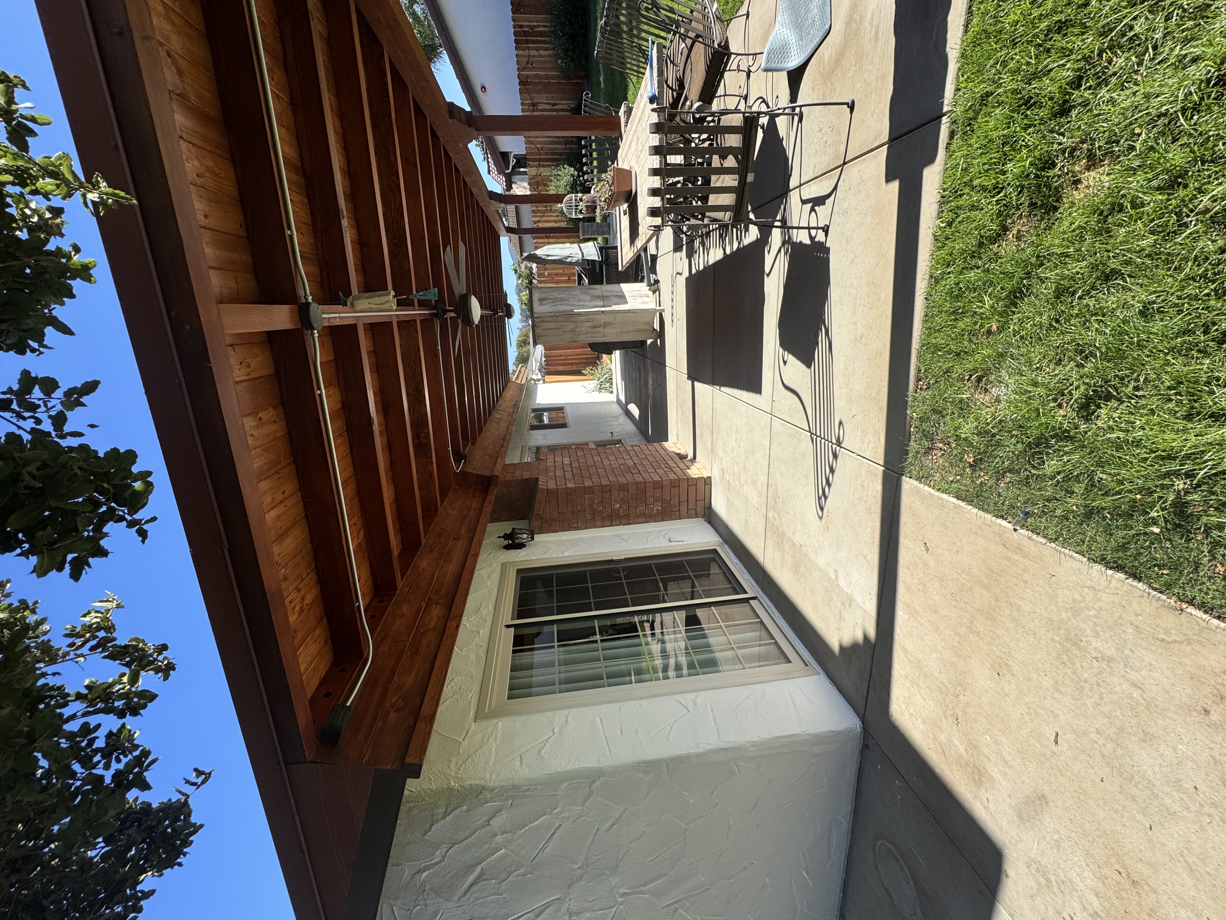 Exterior wall and wood patio cover beside a concrete walkway