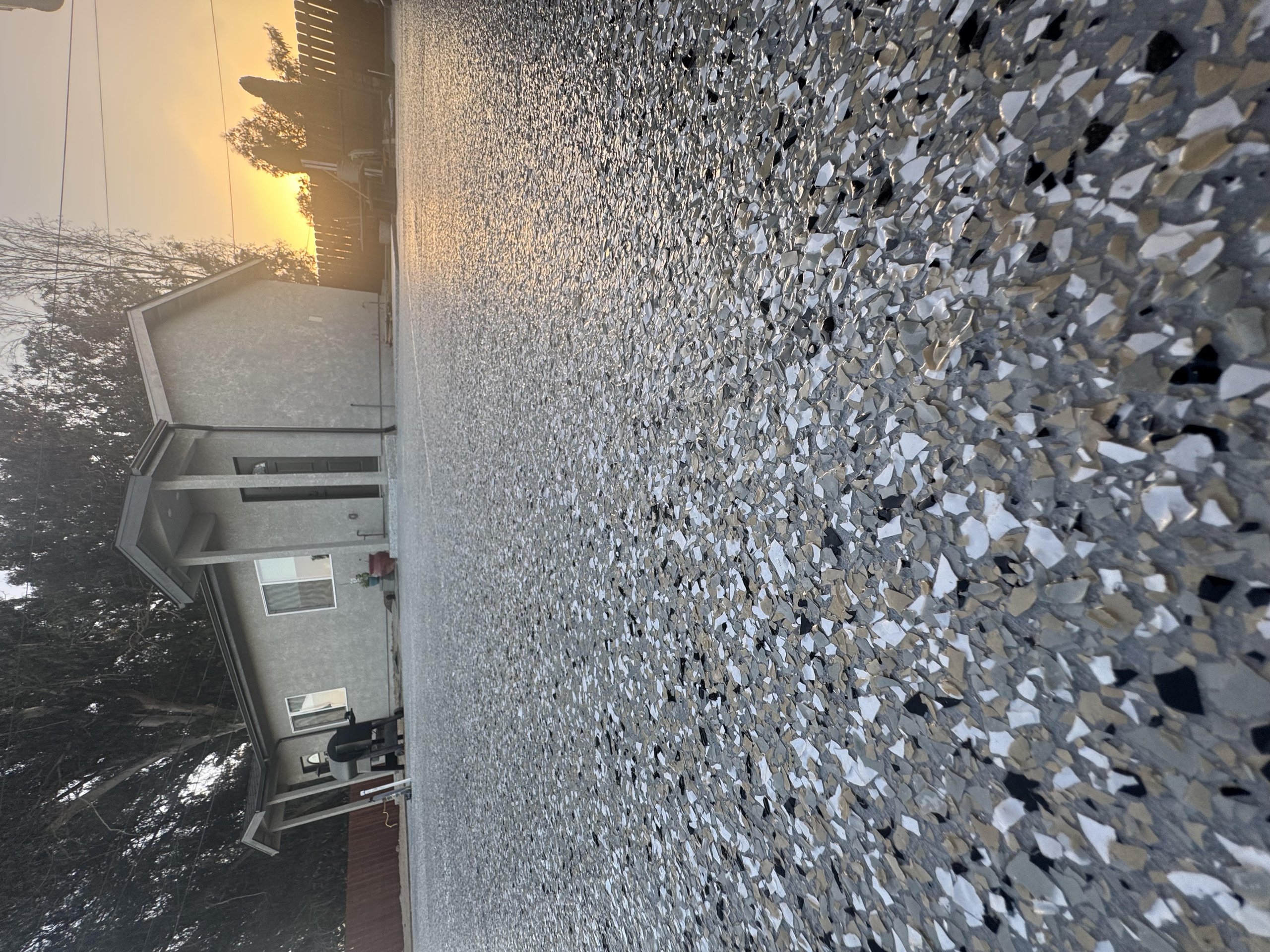 Gray and white decorative flake concrete floor coating viewed in evening light