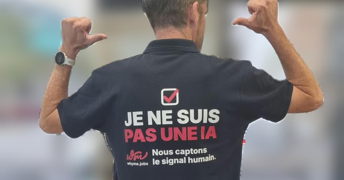 Un membre de l'équipe WhyMe, de dos, montre son polo « Je ne suis pas une IA – Nous captons le signal humain ».