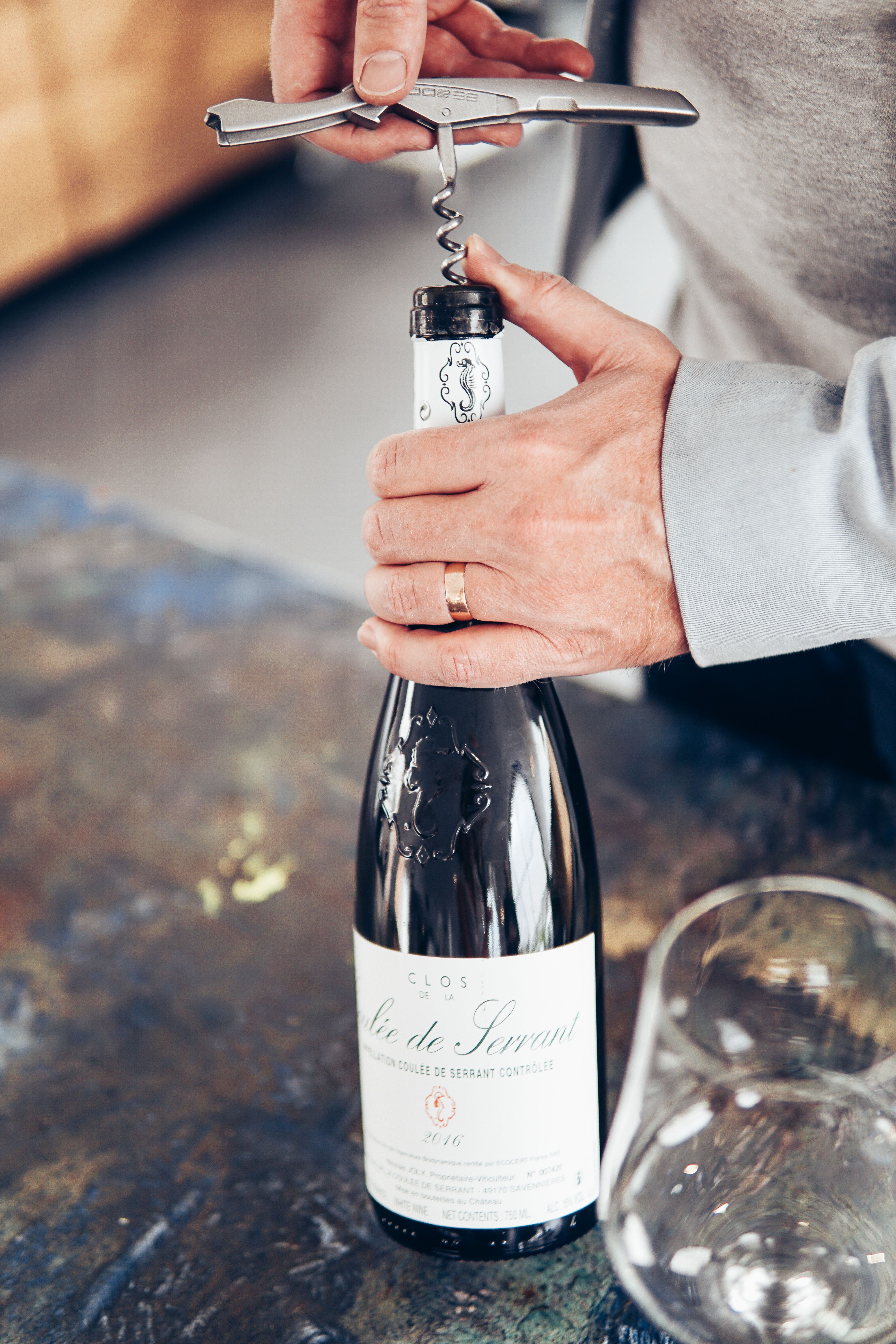 Hands opening a wine bottle with a waiter’s corkscrew