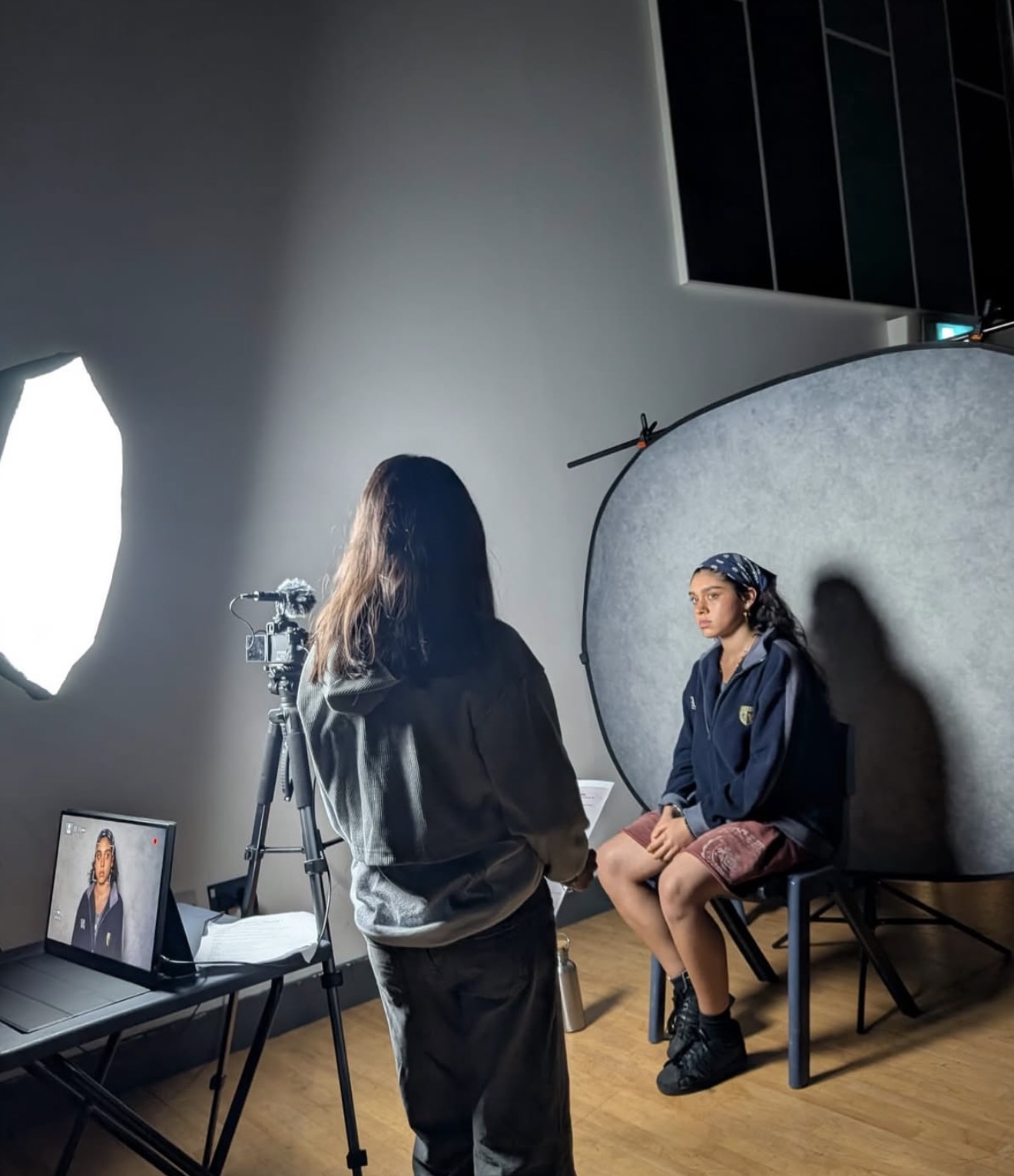 HFTD student being filmed in the studio with a softbox light and the take on the monitor
