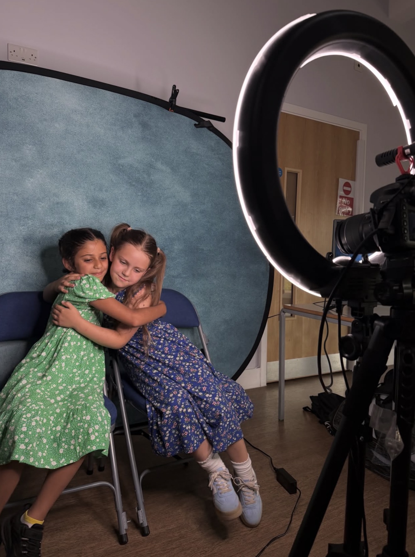 Two HFTD students hugging in front of the backdrop during a class filming session
