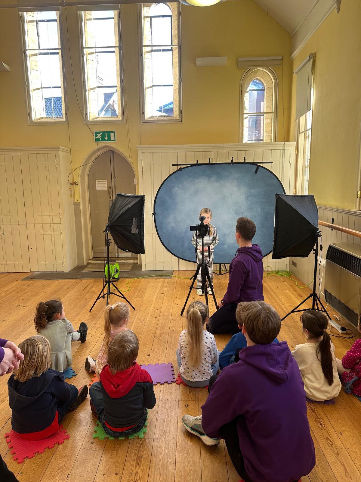 HFTD Minis class: a young student on the blue backdrop being filmed while the others watch