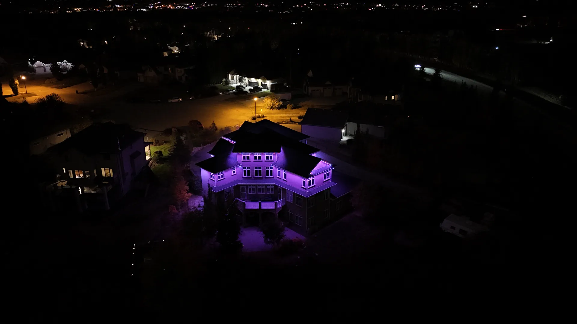 Aerial view of a home lit in purple permanent LED lighting