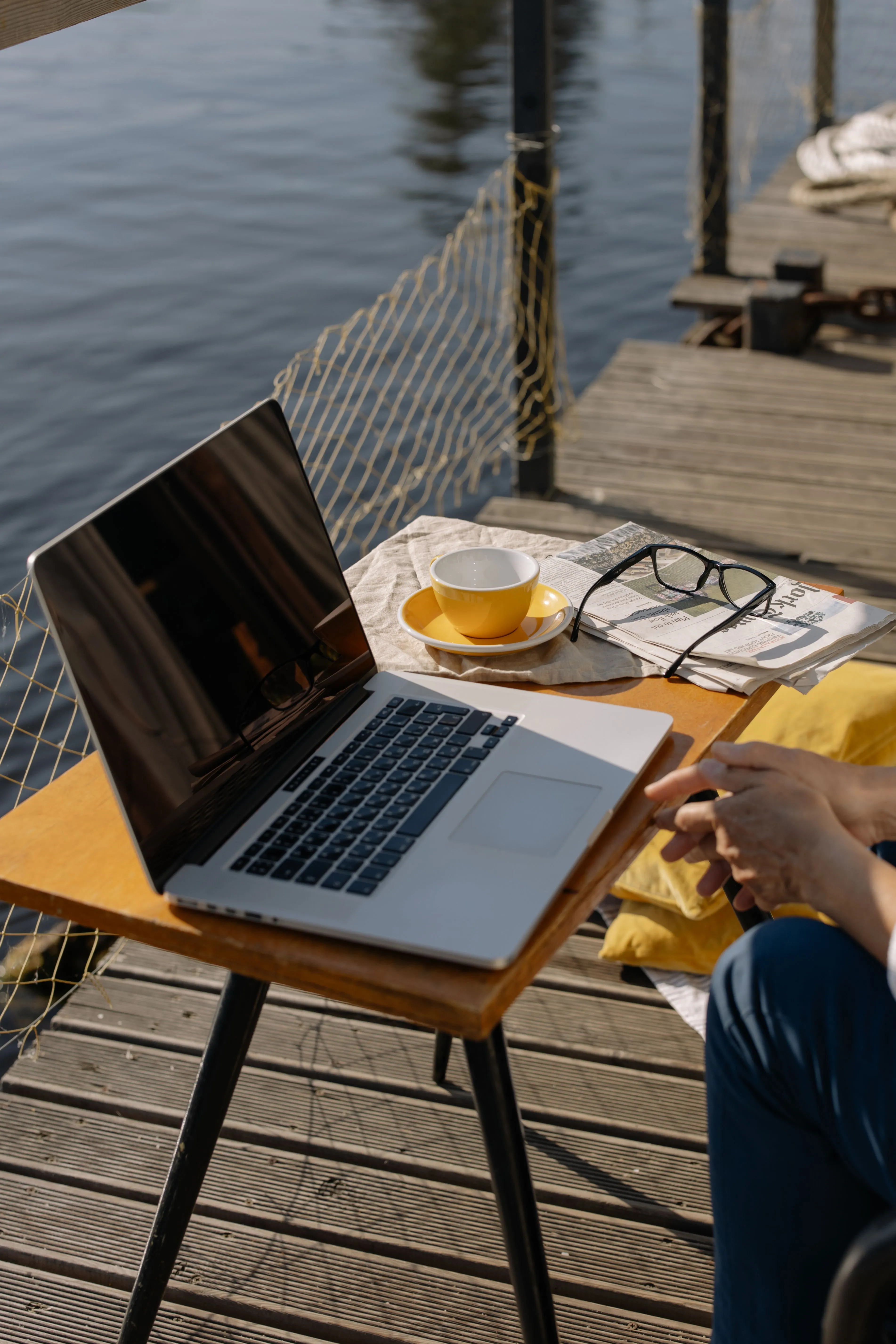 Laptop en een kop koffie op een steiger aan het water