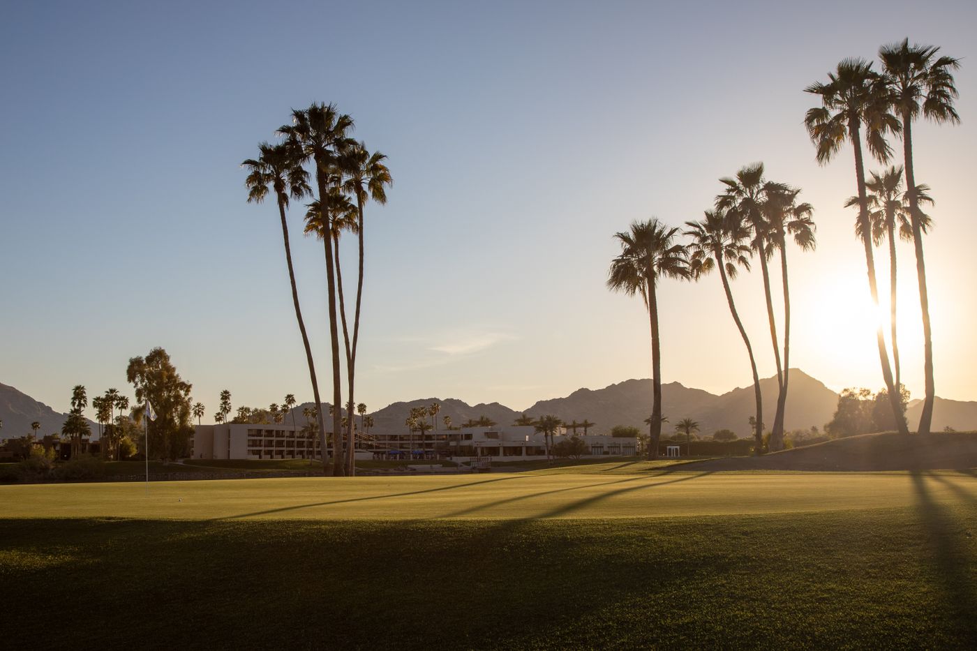Palm trees and mountains on a golf course at sunset