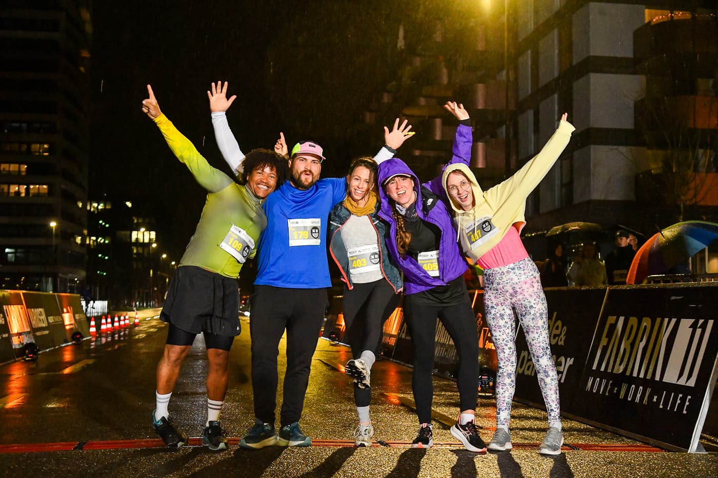 Gruppe von Läuferinnen und Läufern jubelt nach dem NightRun vor dem FABRIK11 Banner in Dübendorf