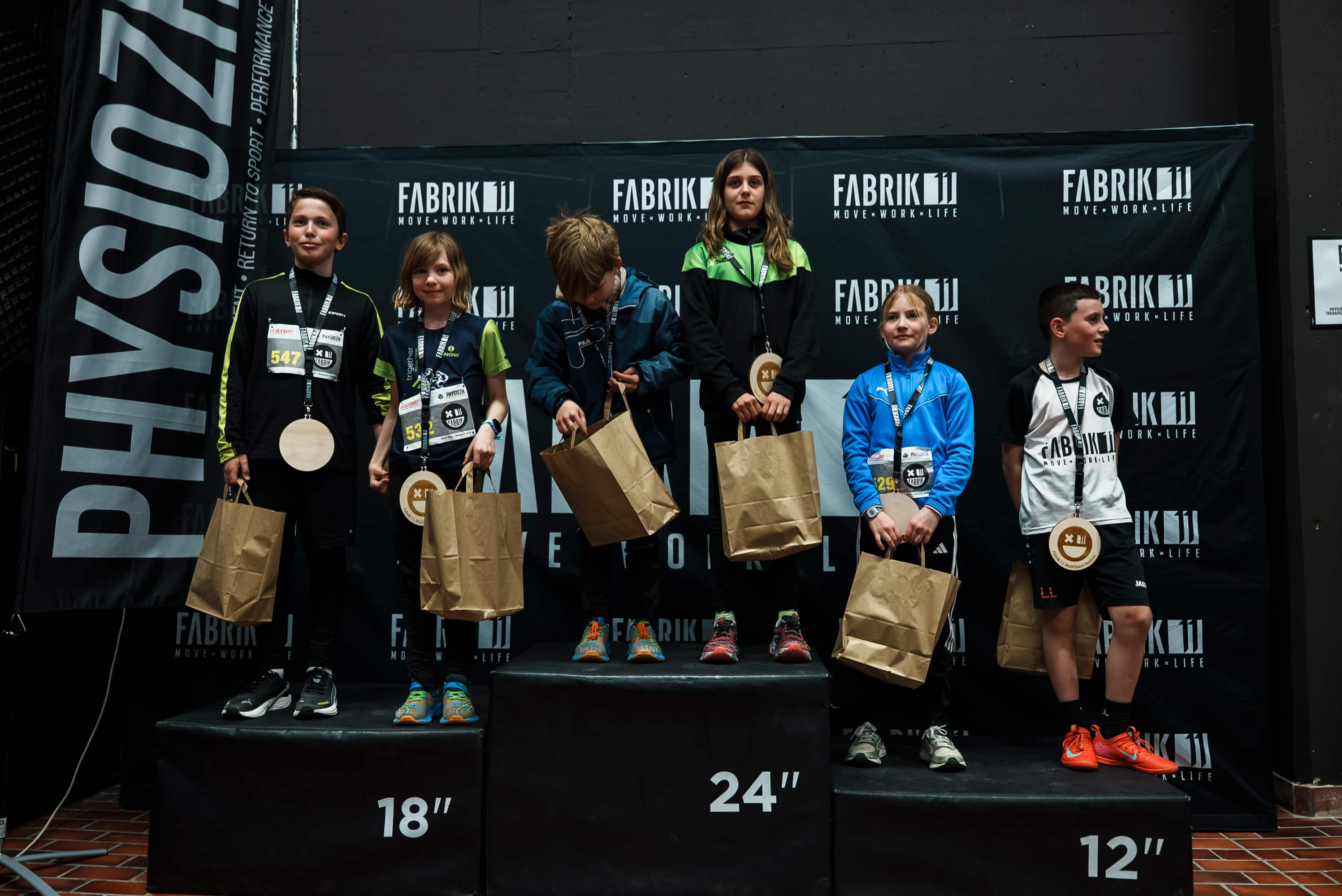 Kinder mit Medaillen auf dem Siegerpodest des Kids Run beim NightRun in Dübendorf