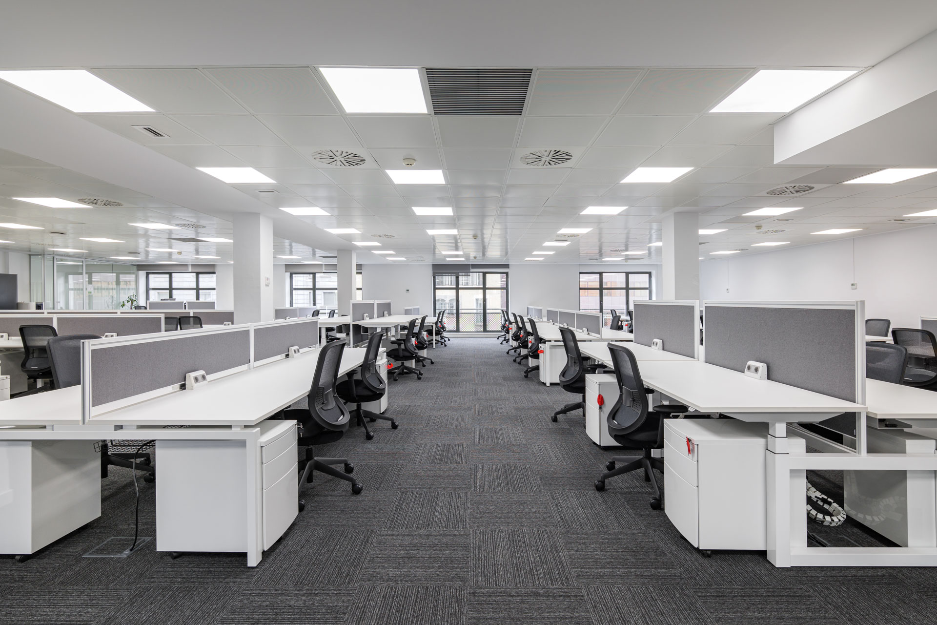 Large, clean open-plan office with rows of white workstations