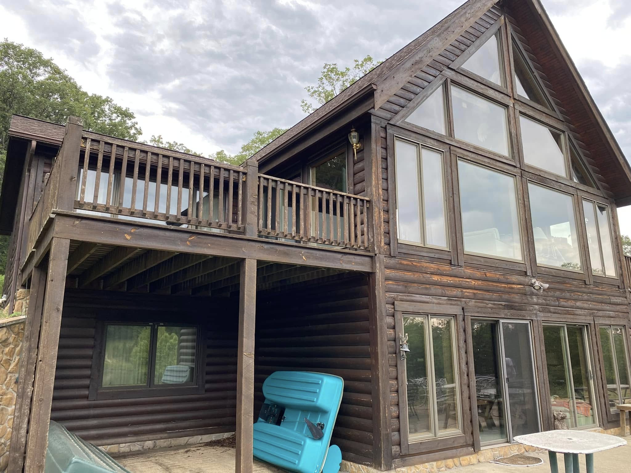 Dark weathered log cabin exterior before cleaning and wood restoration