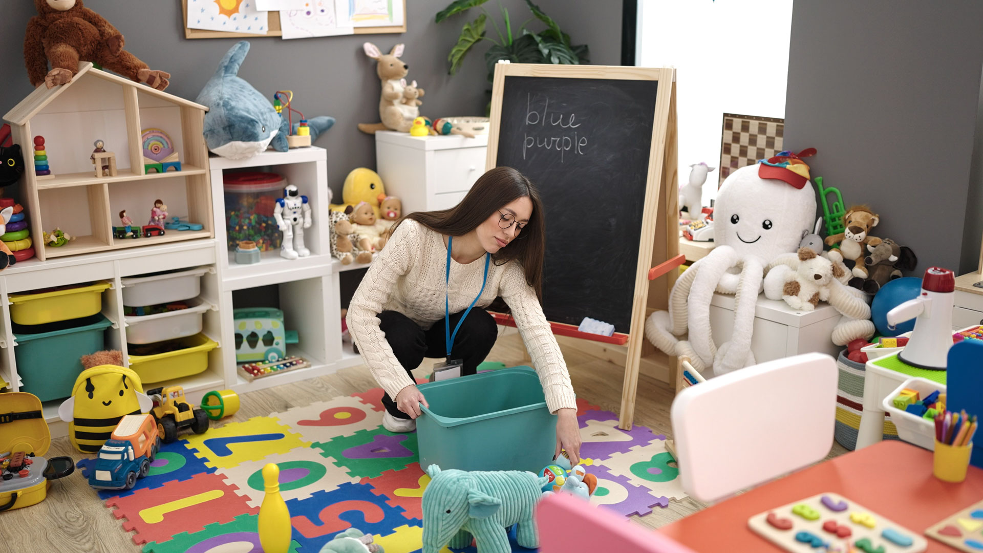 Cleaner tidying a childcare activity room