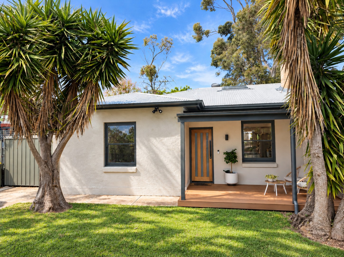Renovated Morphettville home with rendered facade, dark window frames and timber entry deck