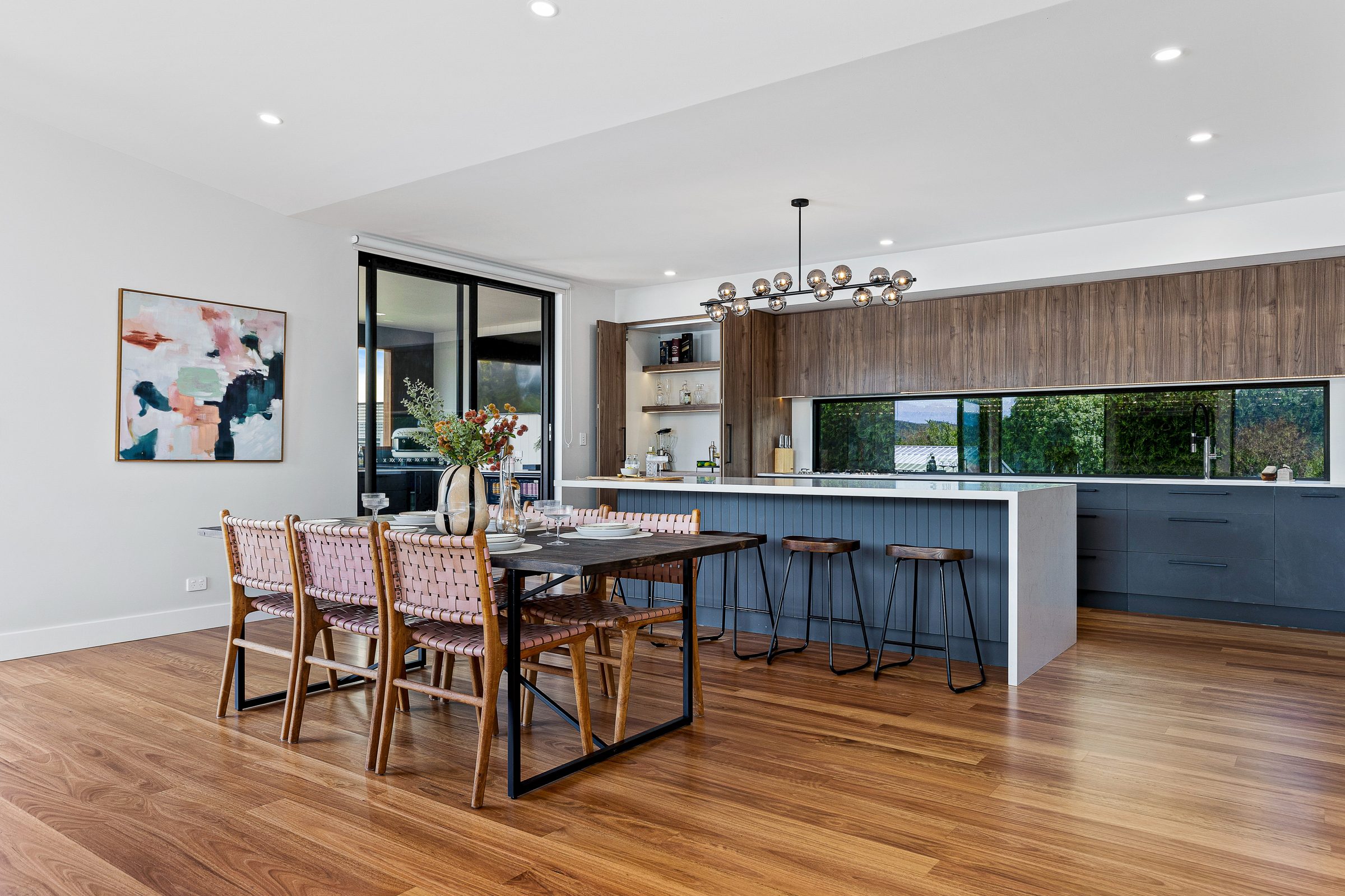 Dining and kitchen in the extension, with blackbutt floor and a long window above the bench