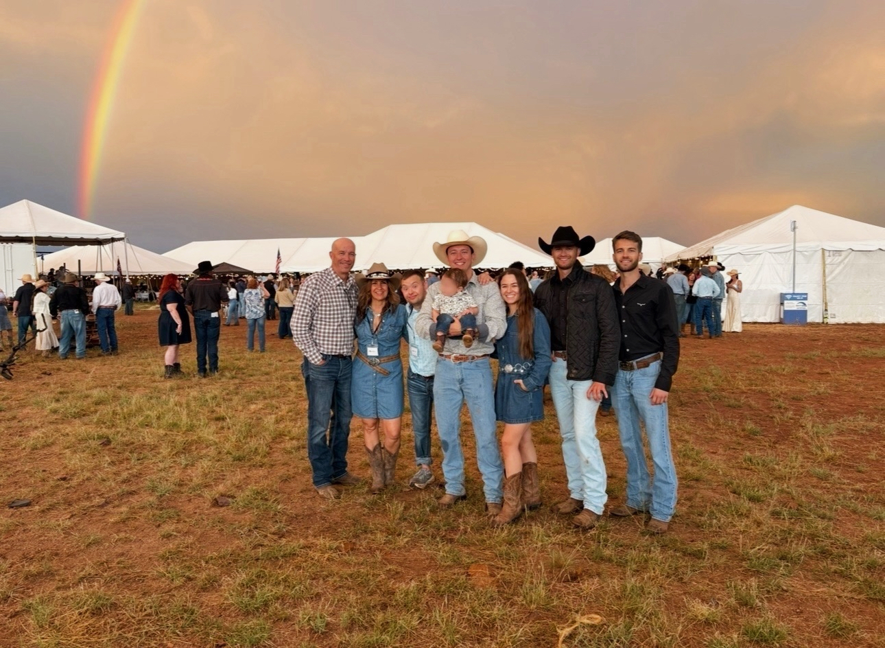 The CSTS family and team together outdoors with a rainbow overhead