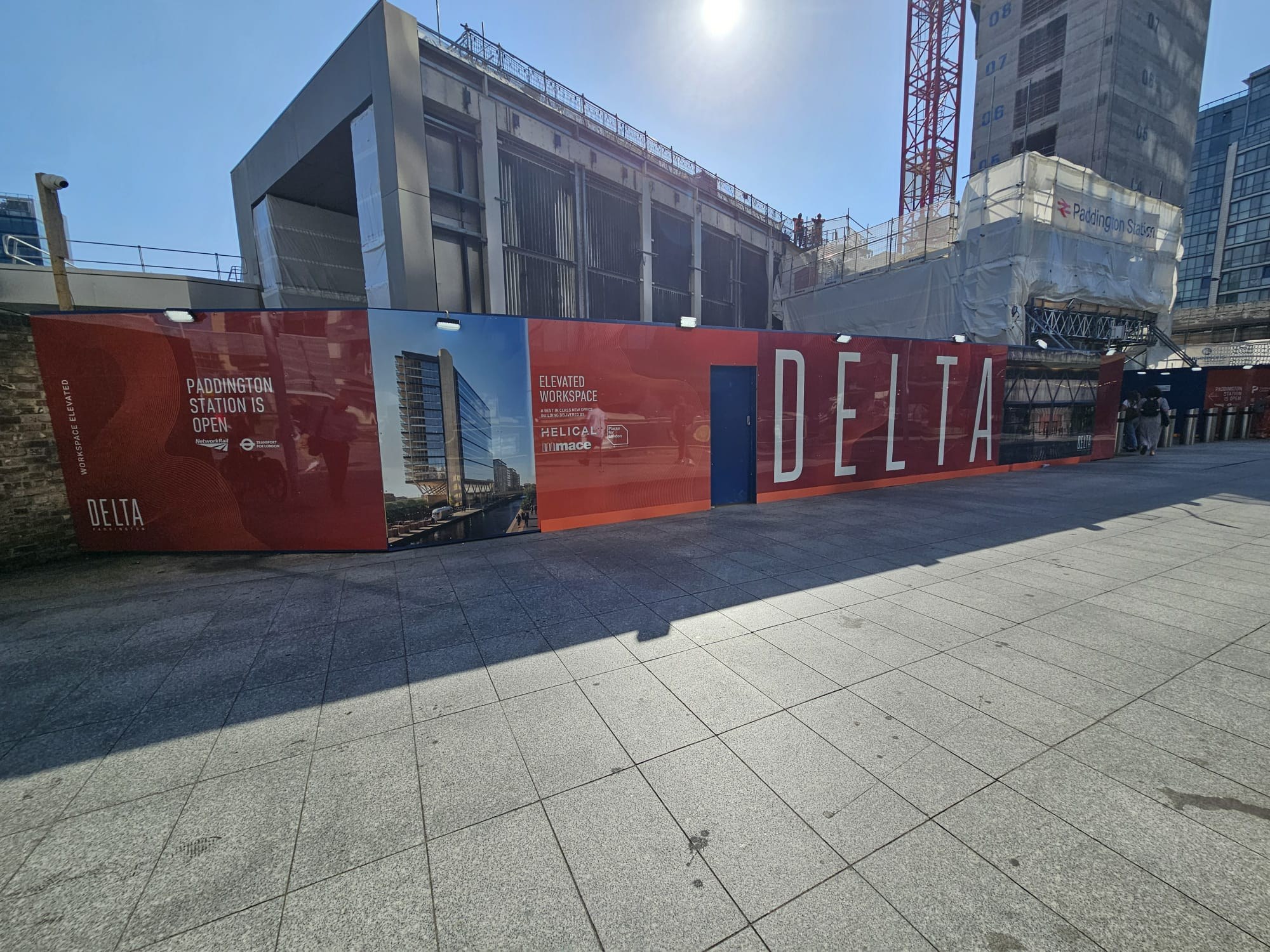 Red DELTA branded hoarding installation outside Paddington Station in London