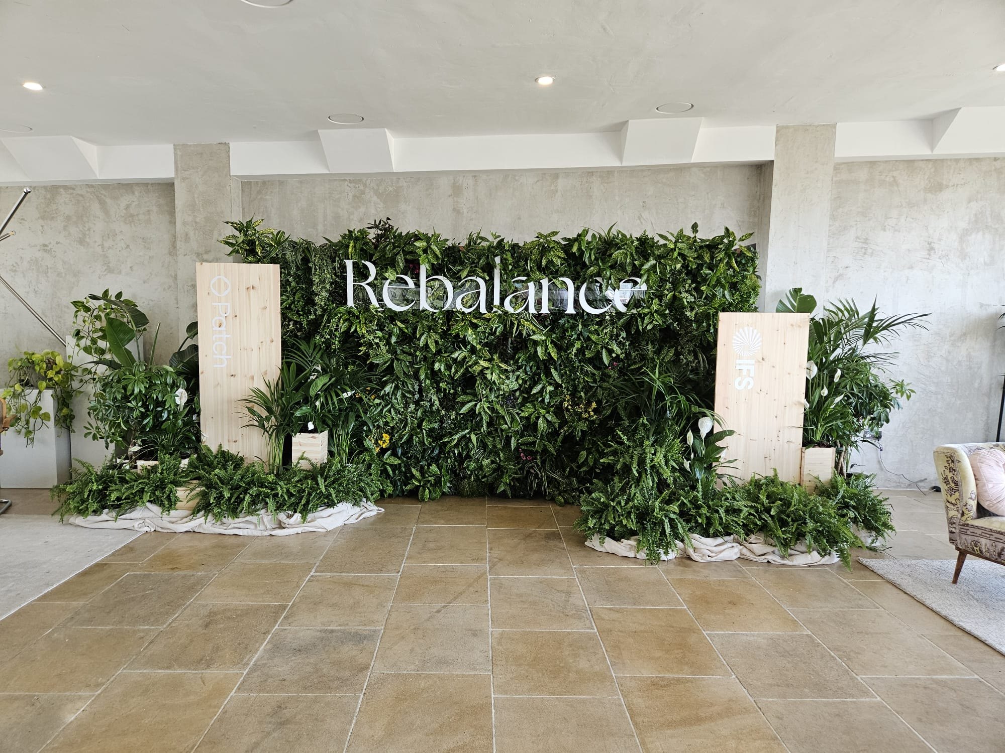Rebalance planted backdrop with green foliage and bespoke pale timber display structures