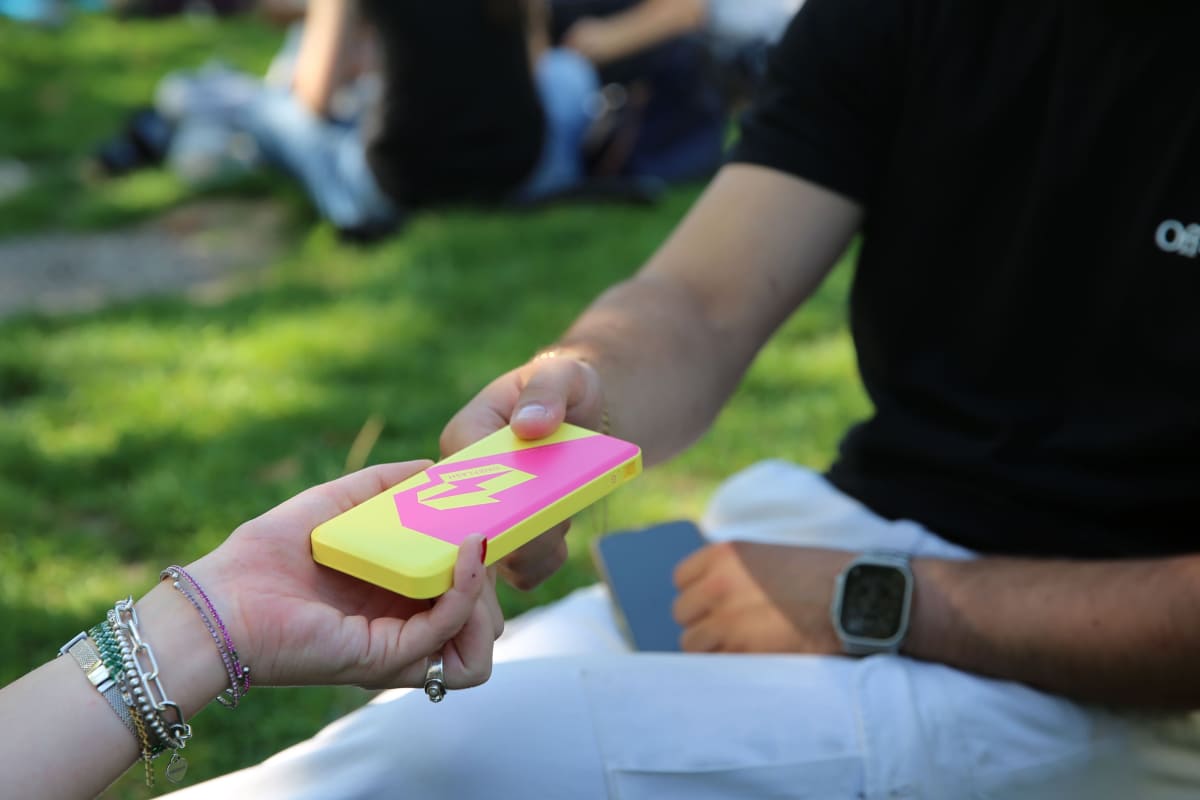 Two people passing a OneFlash power bank hand to hand