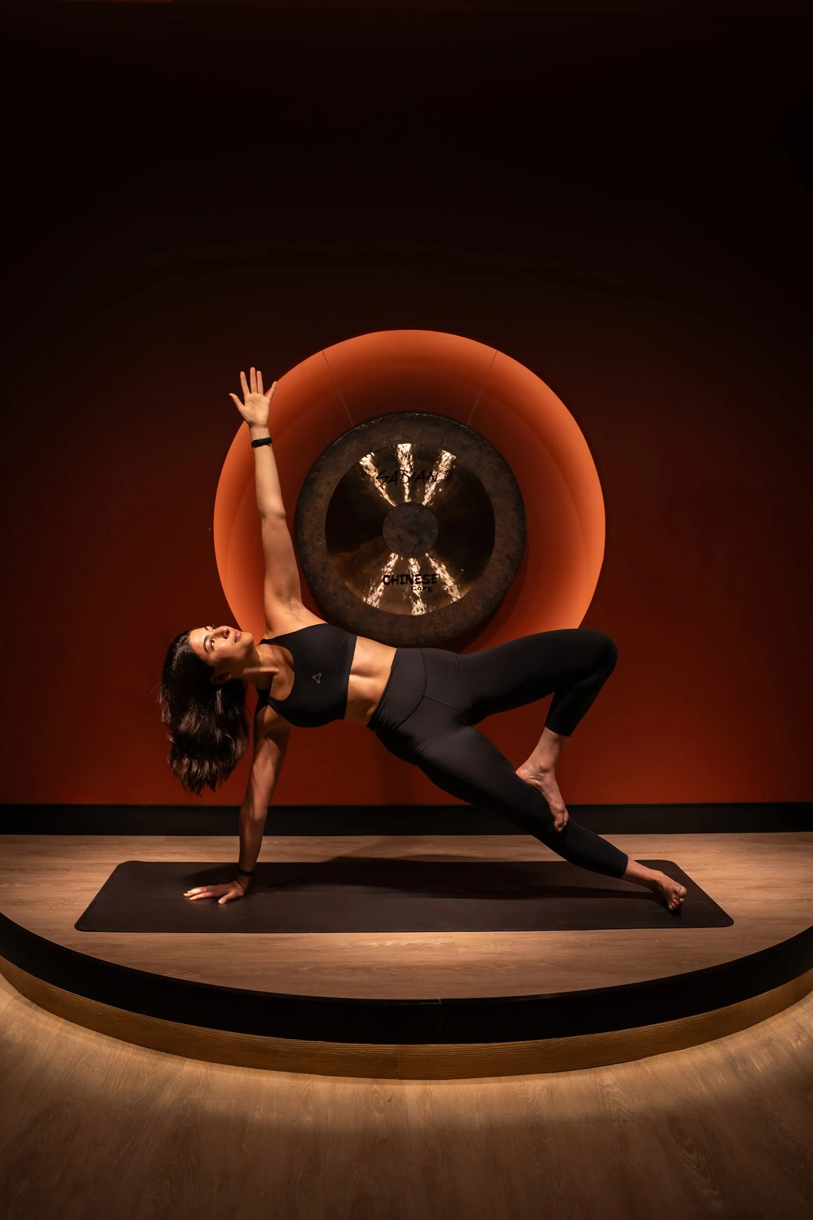 A member holding a side plank under the gong in the Glow studio