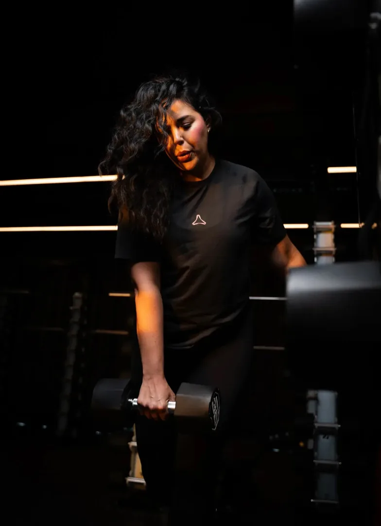 A member training with a dumbbell under low light at AVANT