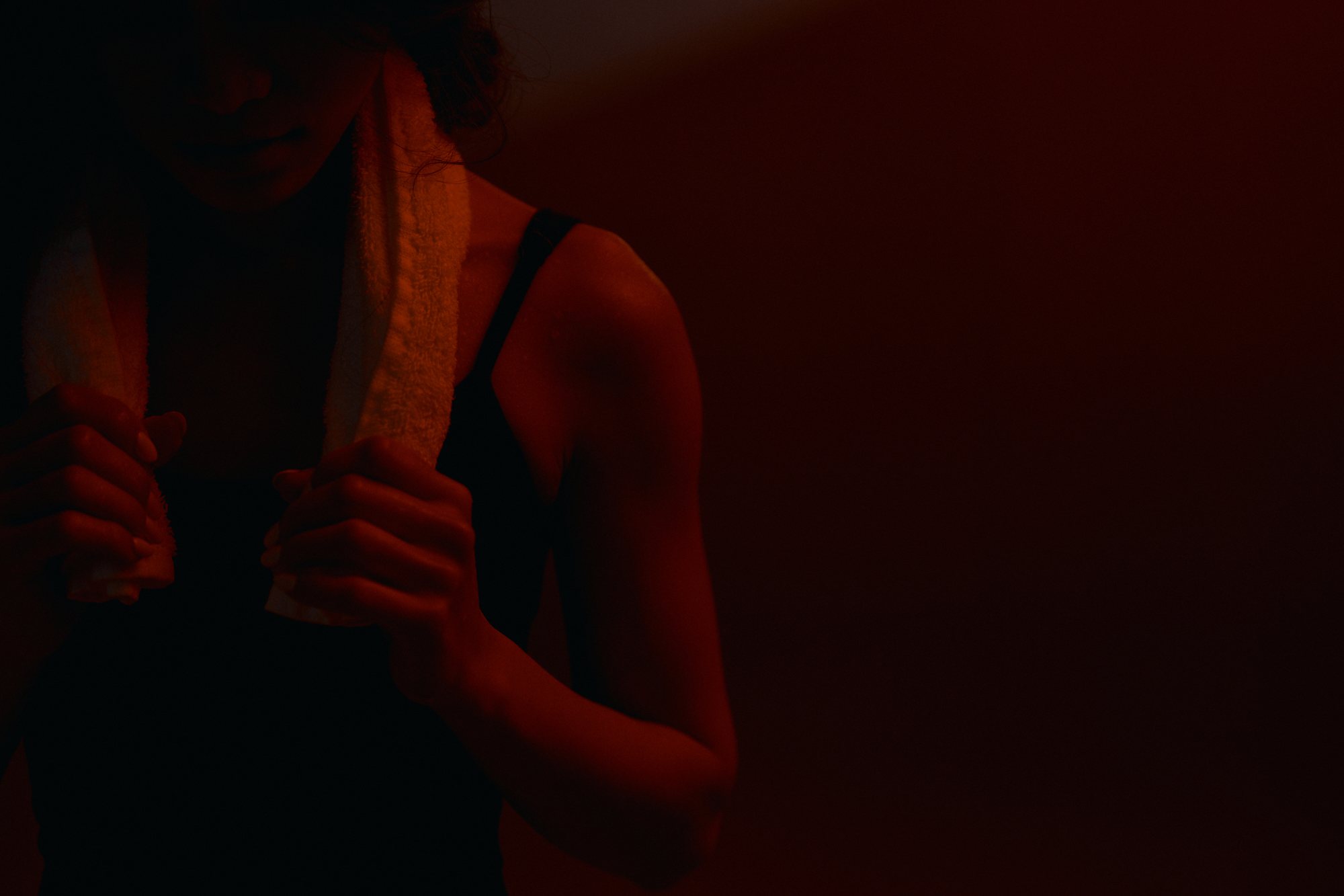 A member with a towel around her neck in warm red light after class