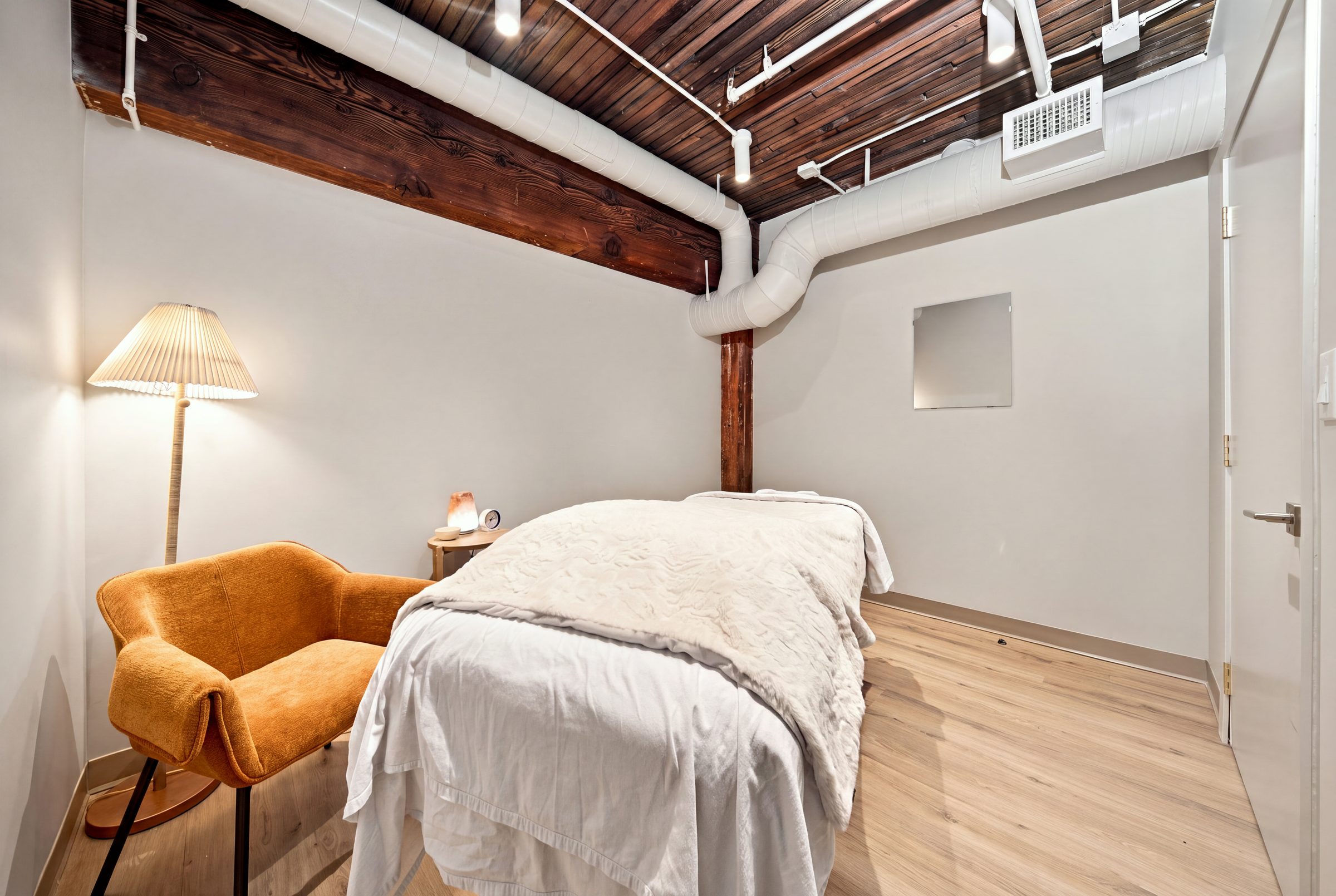 A BNFTS treatment room with a covered table, an armchair and afternoon light under timber beams