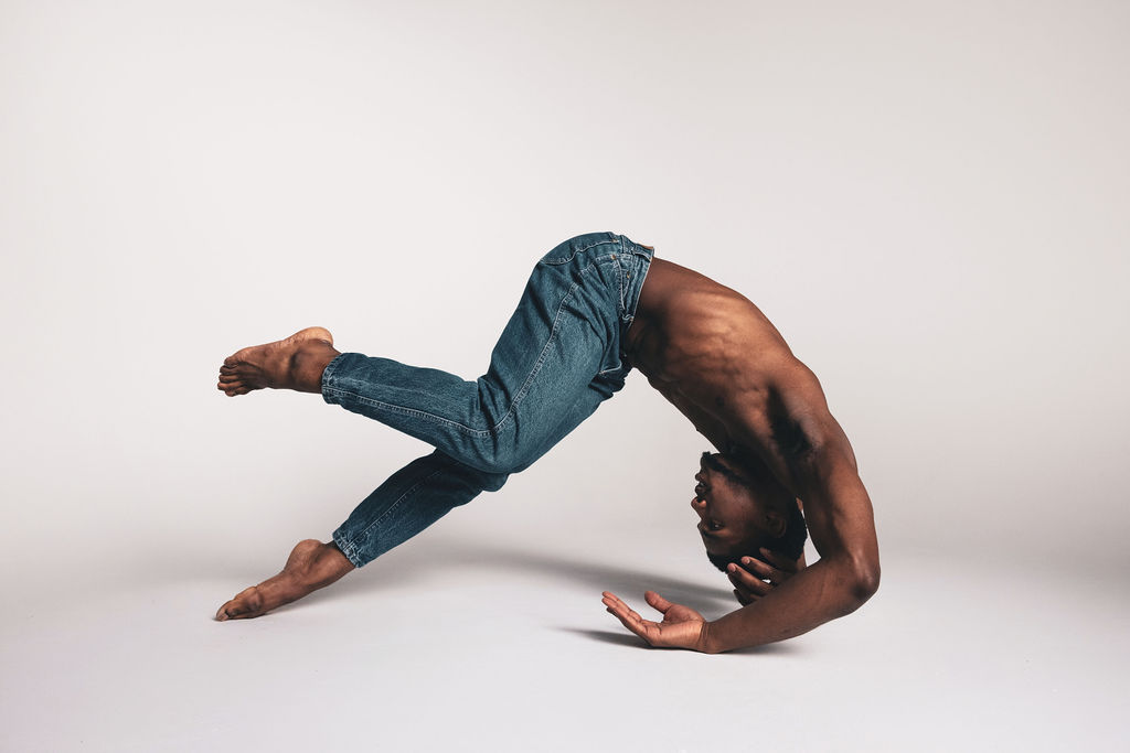 A dancer arched into a bridge on the floor, wearing blue jeans, from the BNFTS studio shoot
