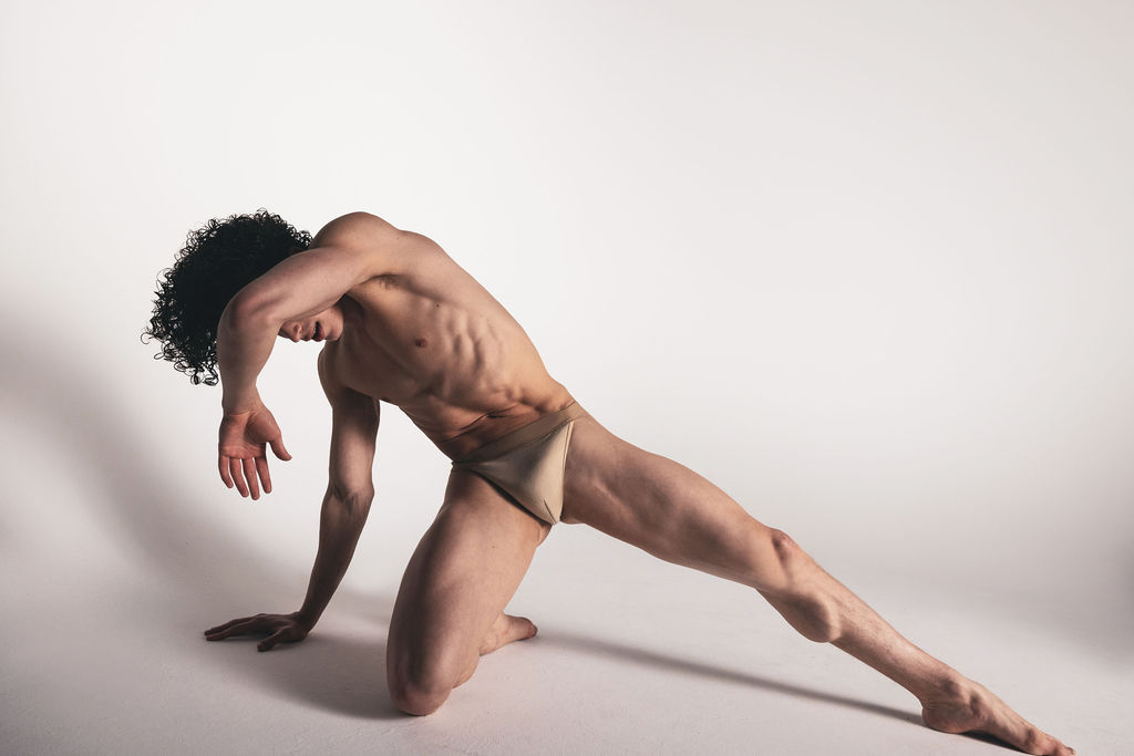A near-nude dancer in a low lunge with their head tucked behind one arm, from the BNFTS Unbound campaign
