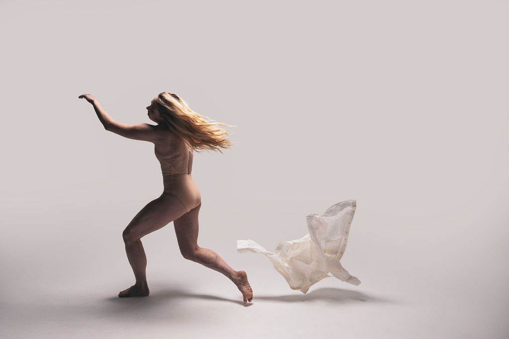 A nude dancer running forward with a length of white fabric trailing behind, from the BNFTS Unbound campaign