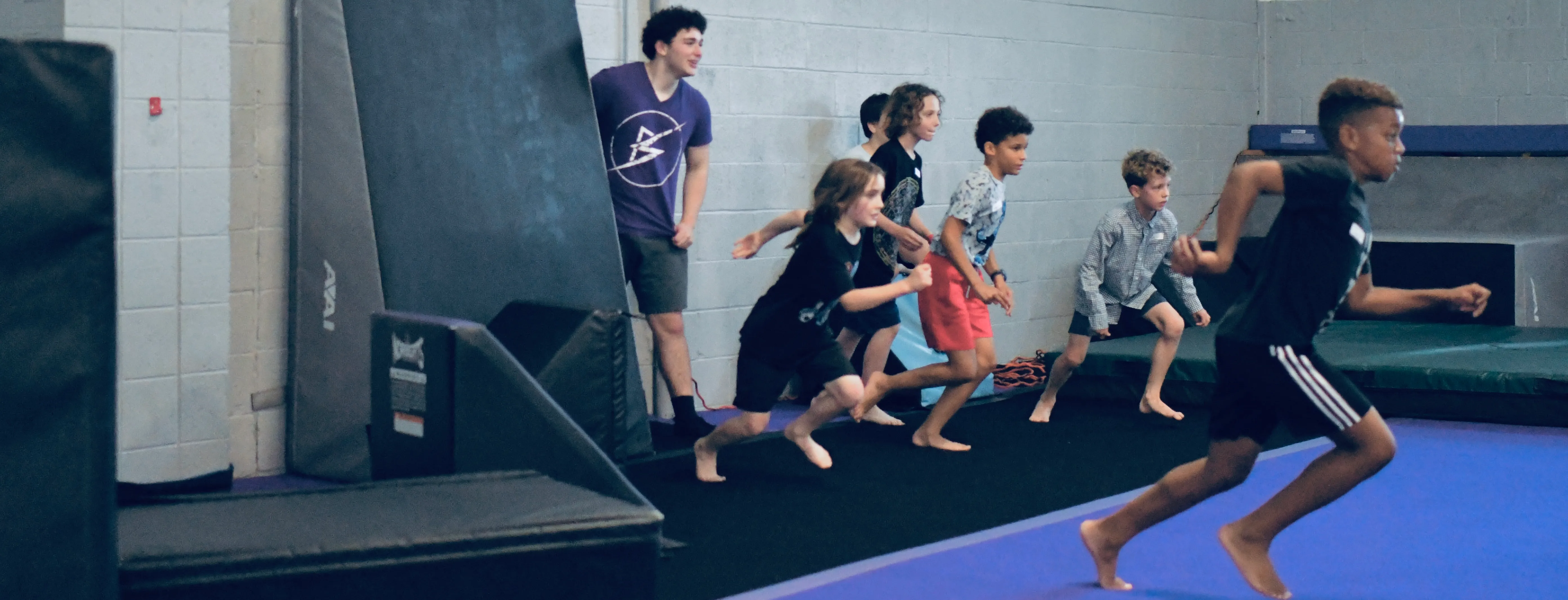 Campers racing across the gym at a Bolt Parkour School's Out camp