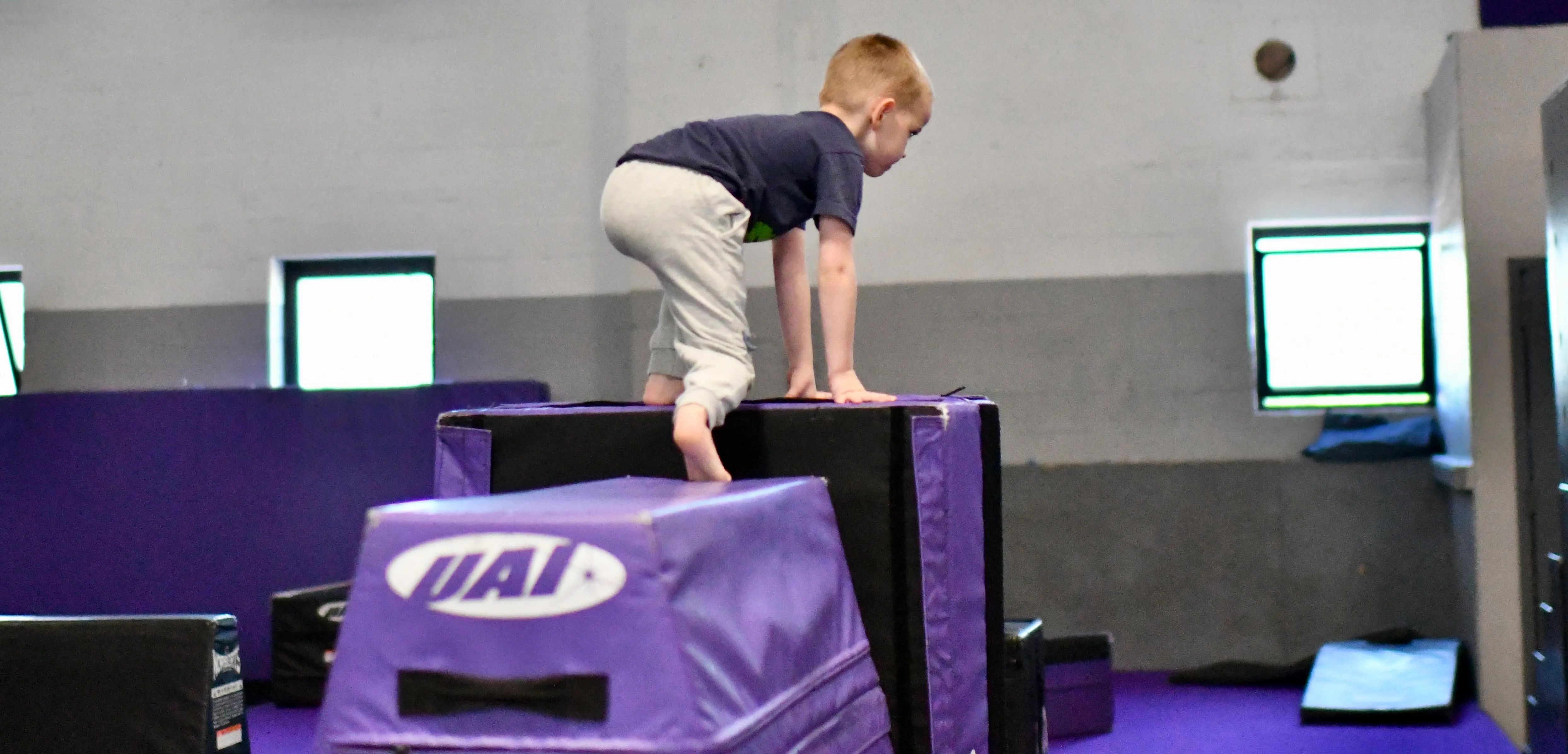 Preschooler climbing onto a soft block at Bolt Parkour