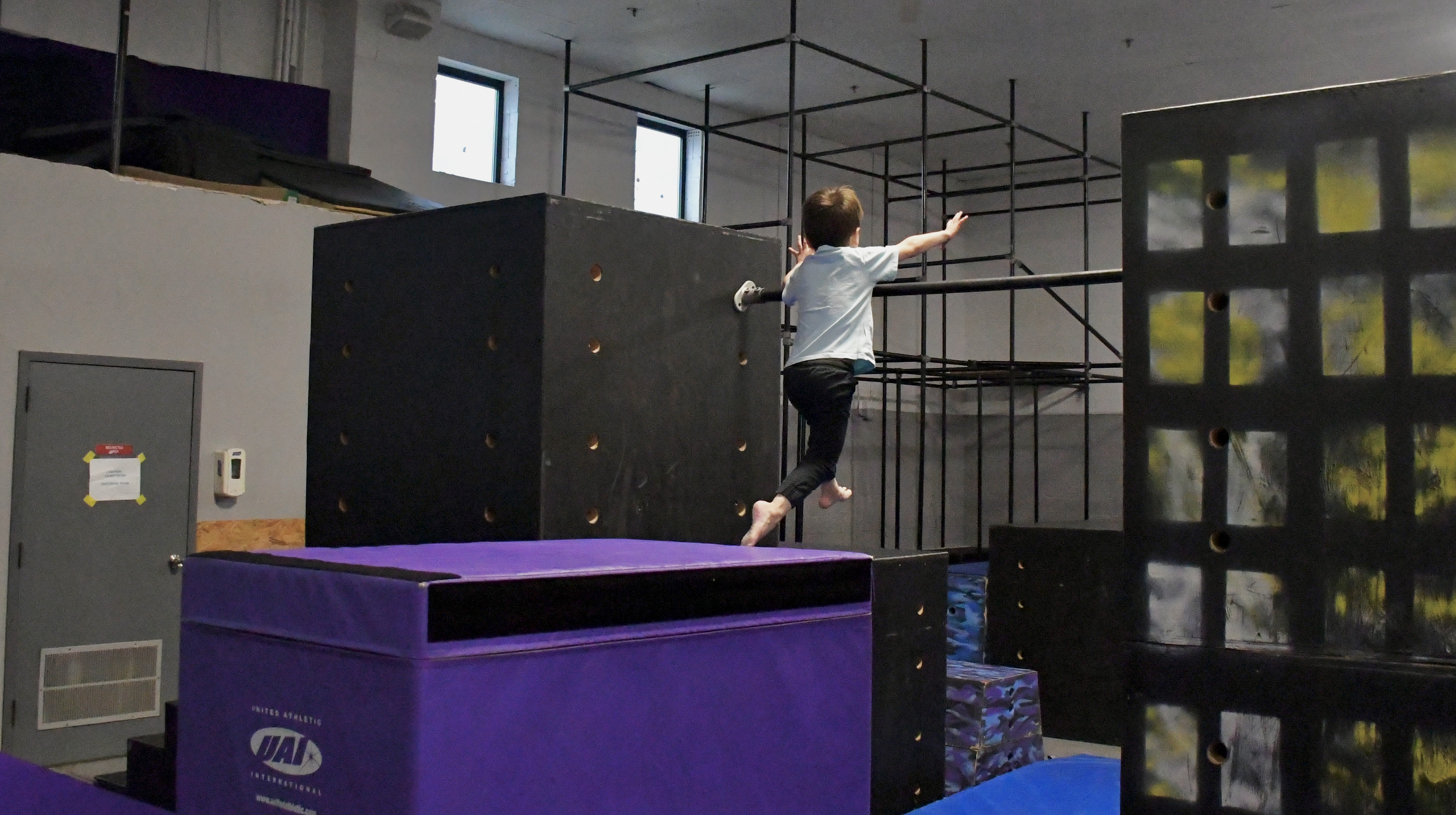 Kid practicing a flip on padded equipment at Bolt Parkour