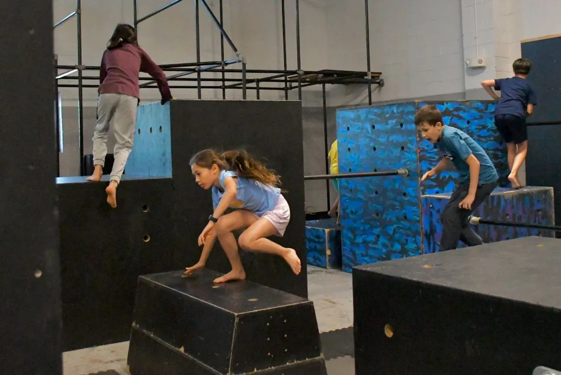 Kids jumping and climbing on parkour boxes in Parkour Basics