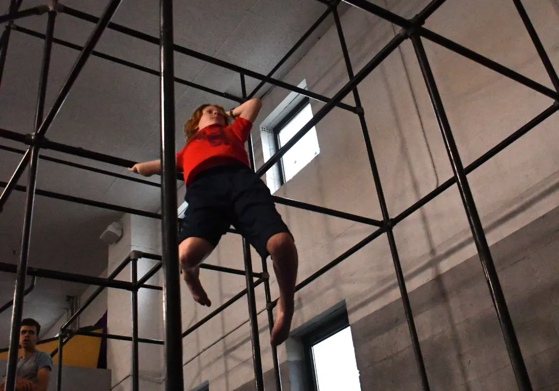 Athlete climbing the steel rig in Intermediate Parkour