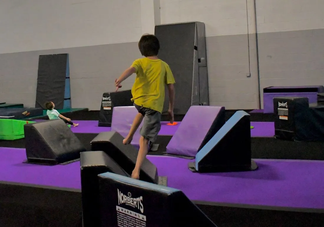 Beginner running a line over soft obstacles in Introductory Parkour