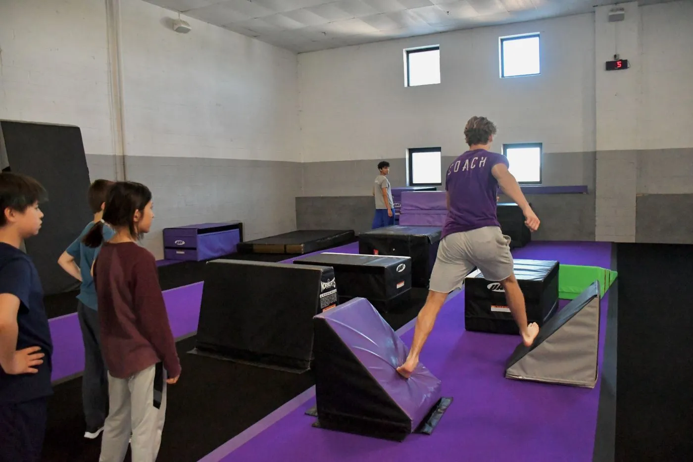 Bolt coach demonstrating a step vault while students watch